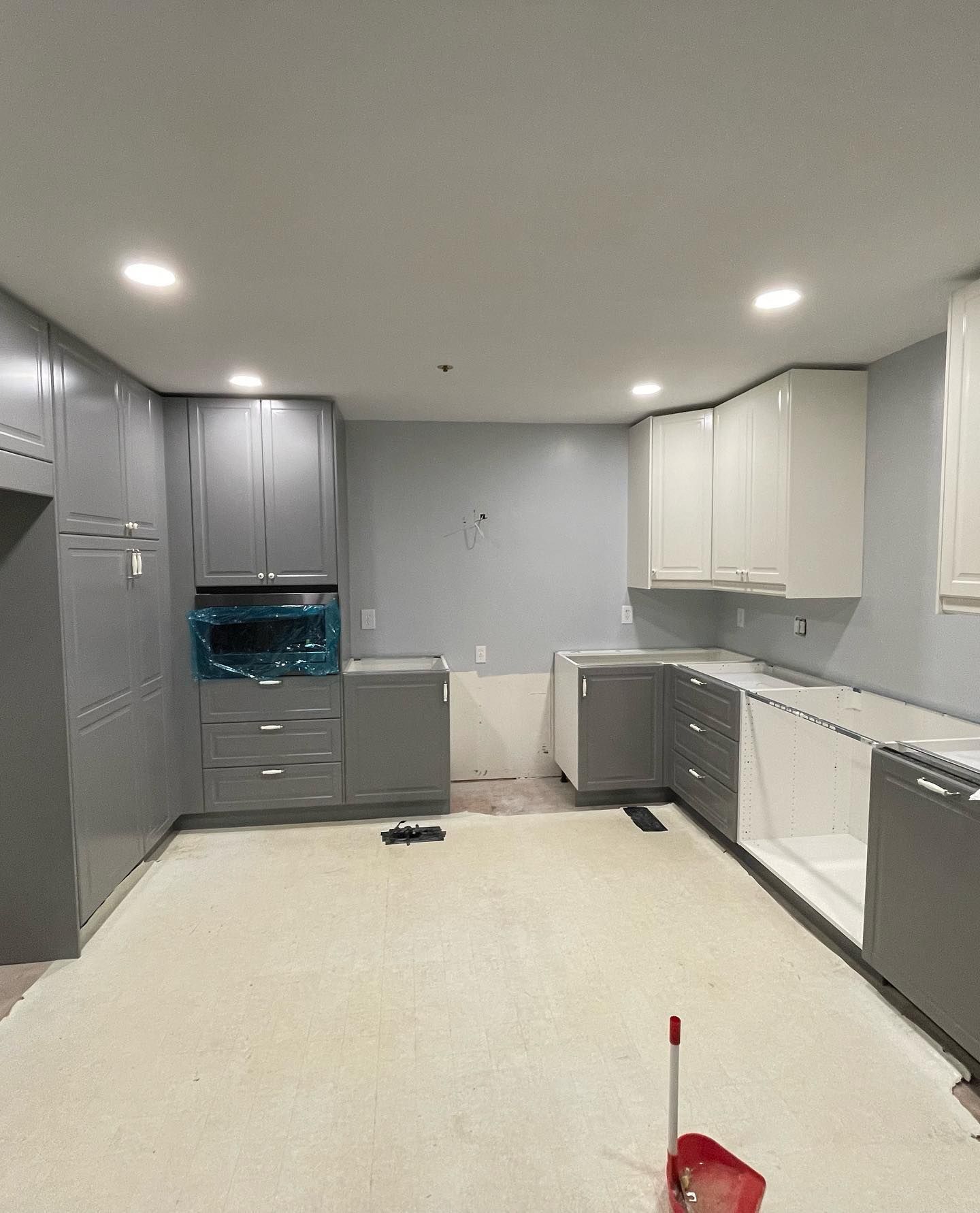 A kitchen with gray cabinets and white counter tops