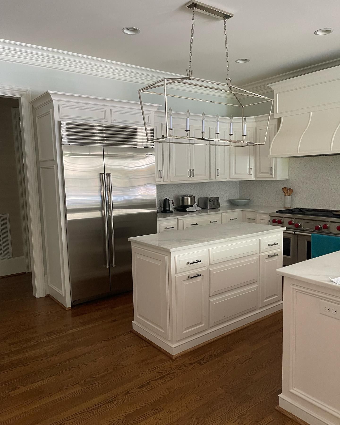 A kitchen with white cabinets , stainless steel appliances , and a large island.