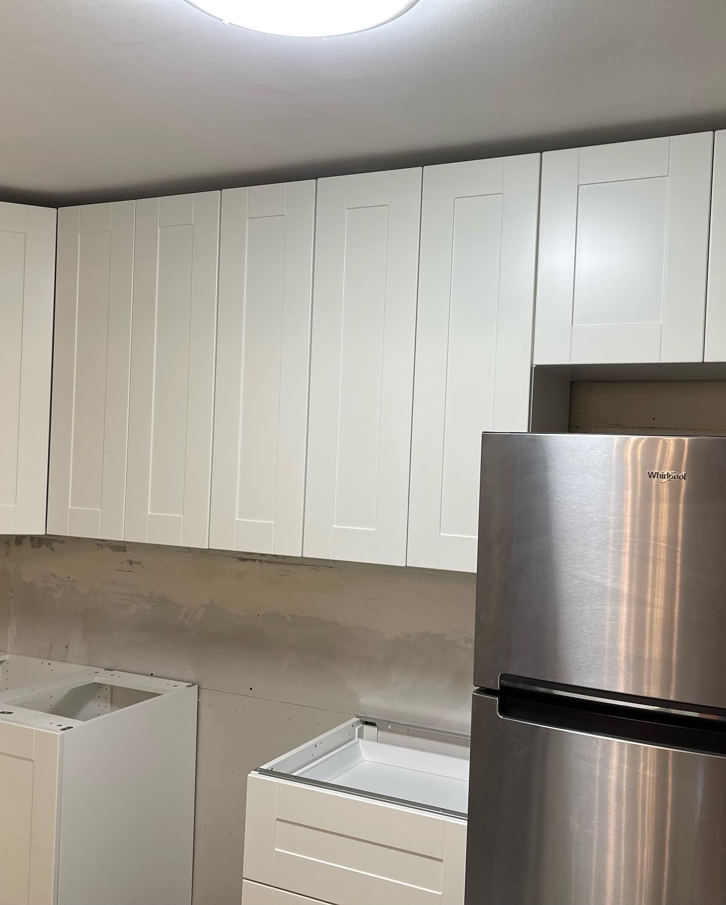 A kitchen with white cabinets and a stainless steel refrigerator