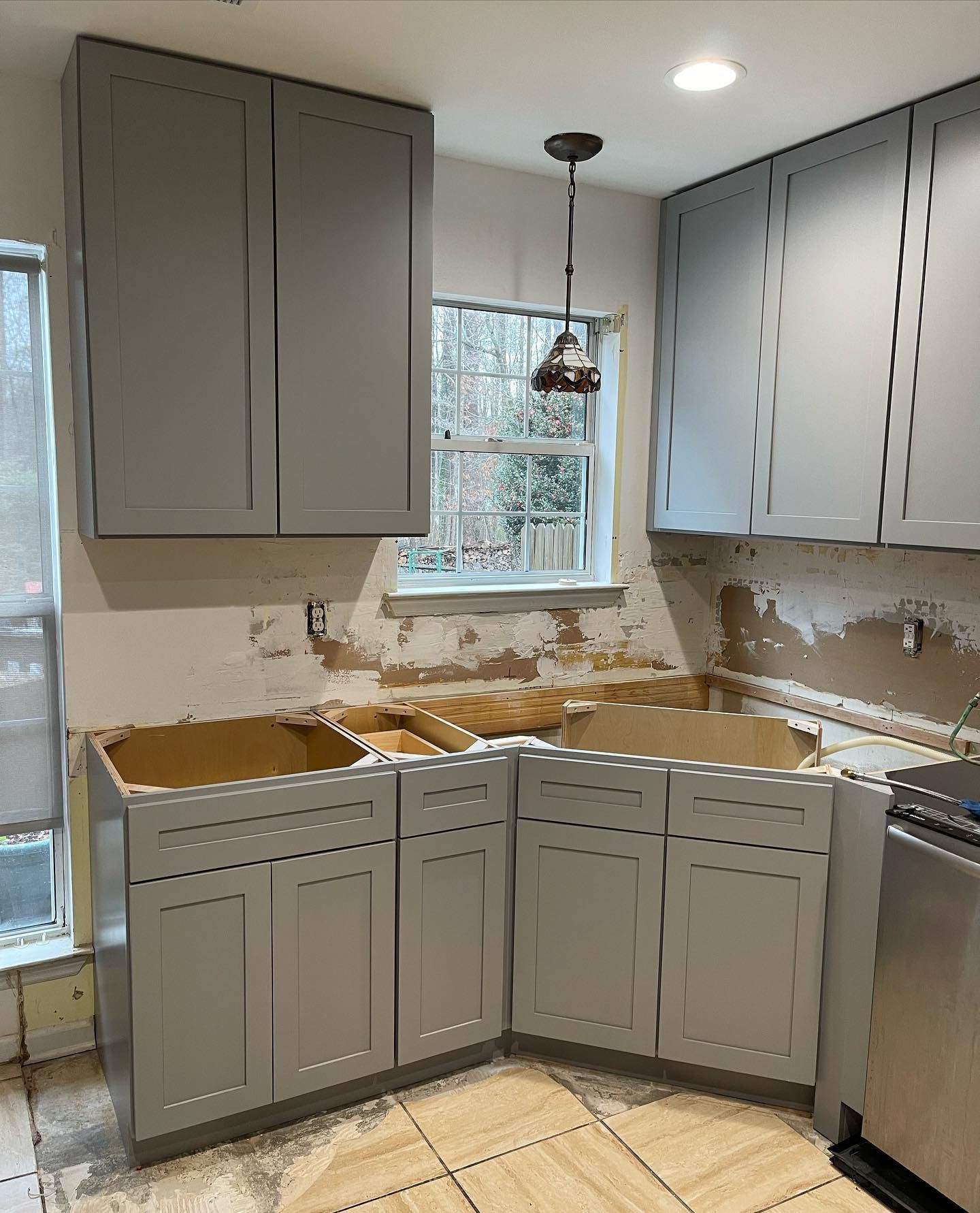 A kitchen with gray cabinets and a window.