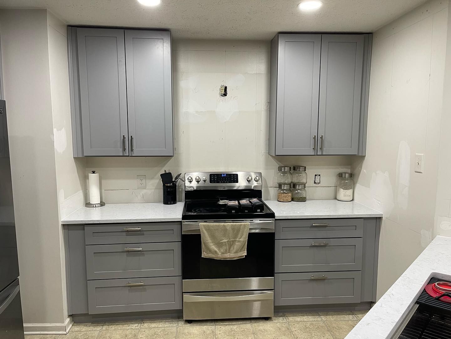A kitchen with stainless steel appliances and gray cabinets.