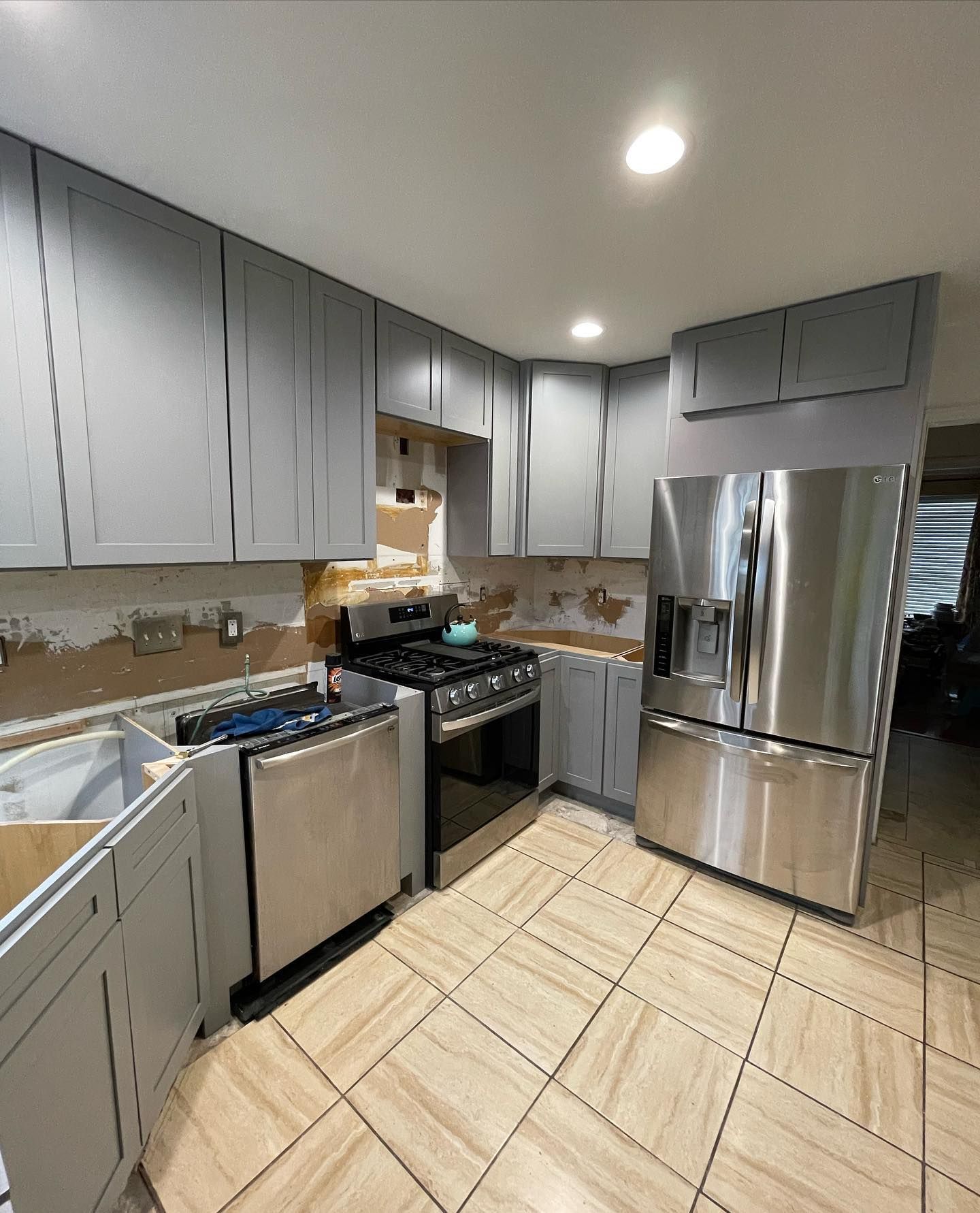 A kitchen with stainless steel appliances and gray cabinets.