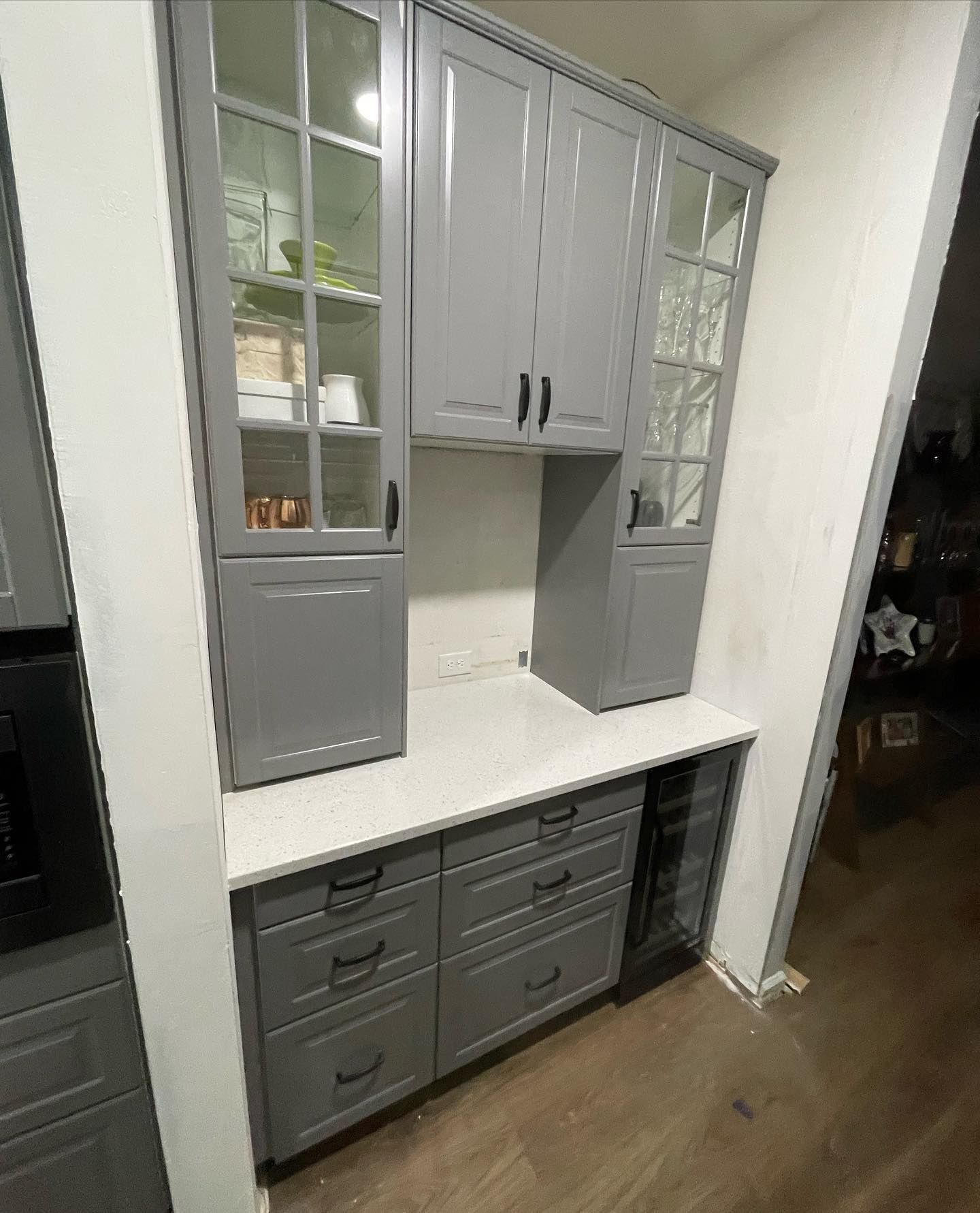 A kitchen with gray cabinets and white counter tops.