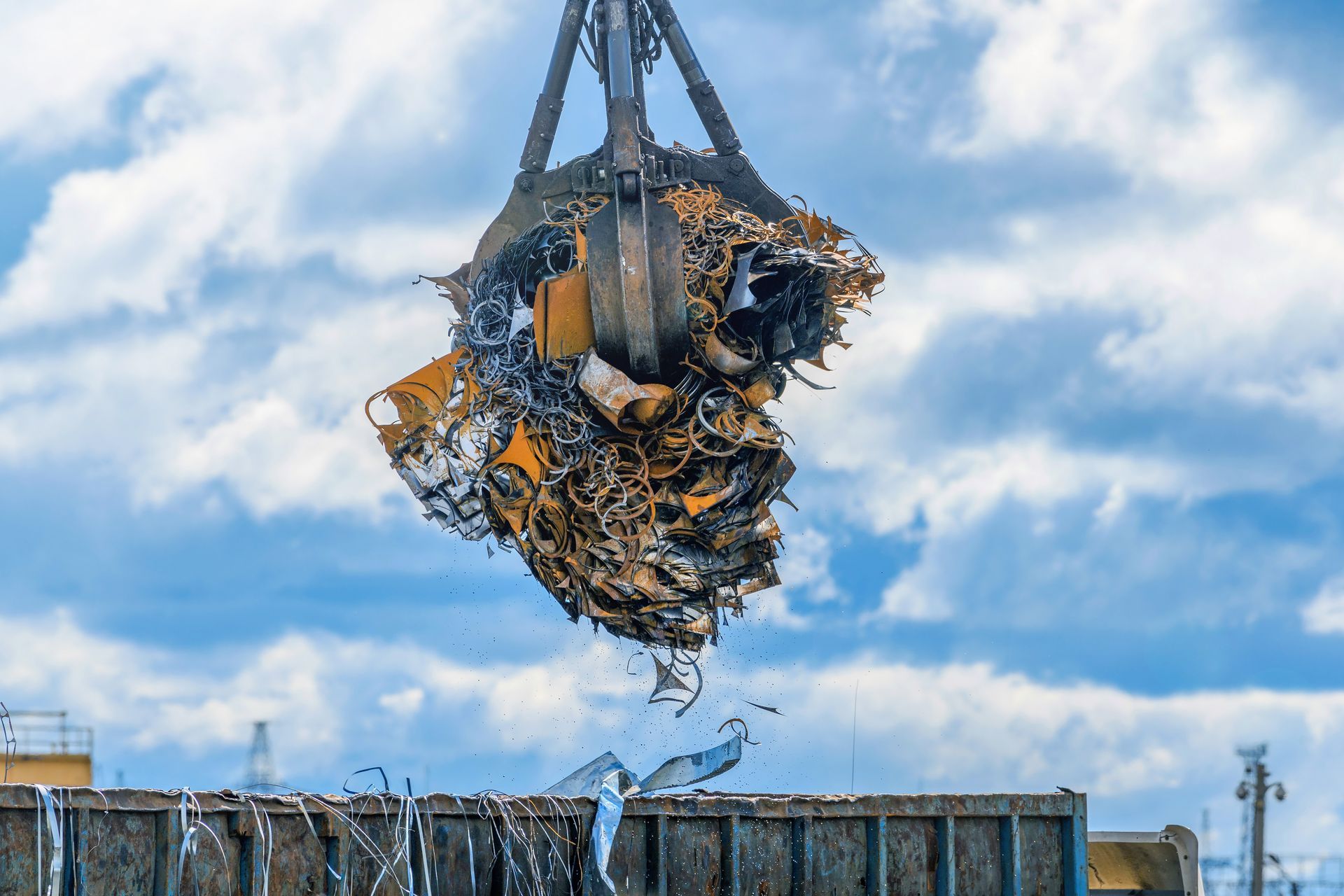 Industrial crane using a large electromagnet to lift a massive bundle of mixed scrap metal above a r