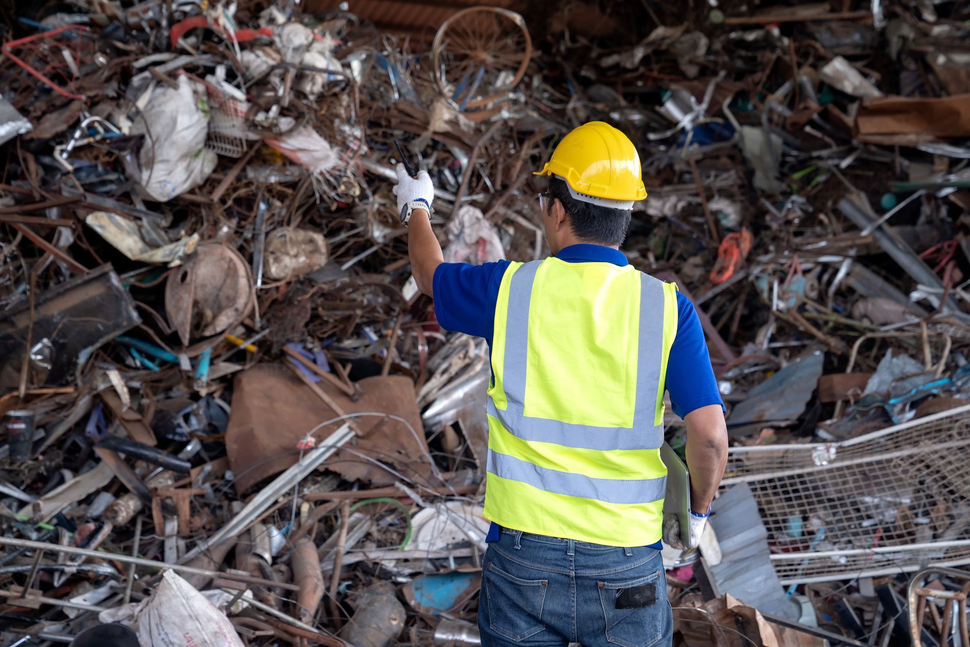 A man in a yellow vest stands among scrap metal at Sunwest Metals Inc, a leader in metal recycling