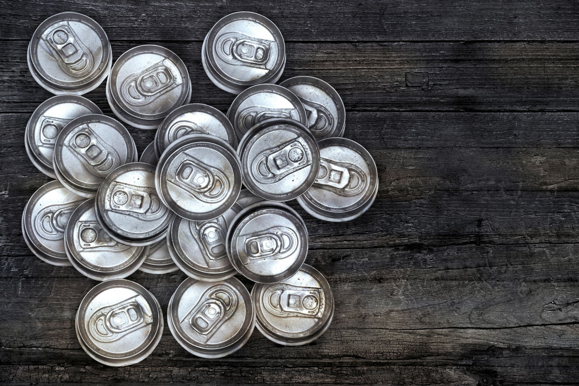 Aluminum can tops on rustic wood table, recycling symbol for sustainability and eco-friendly living.