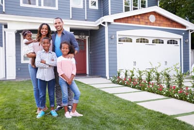 Happy family standing outside their house