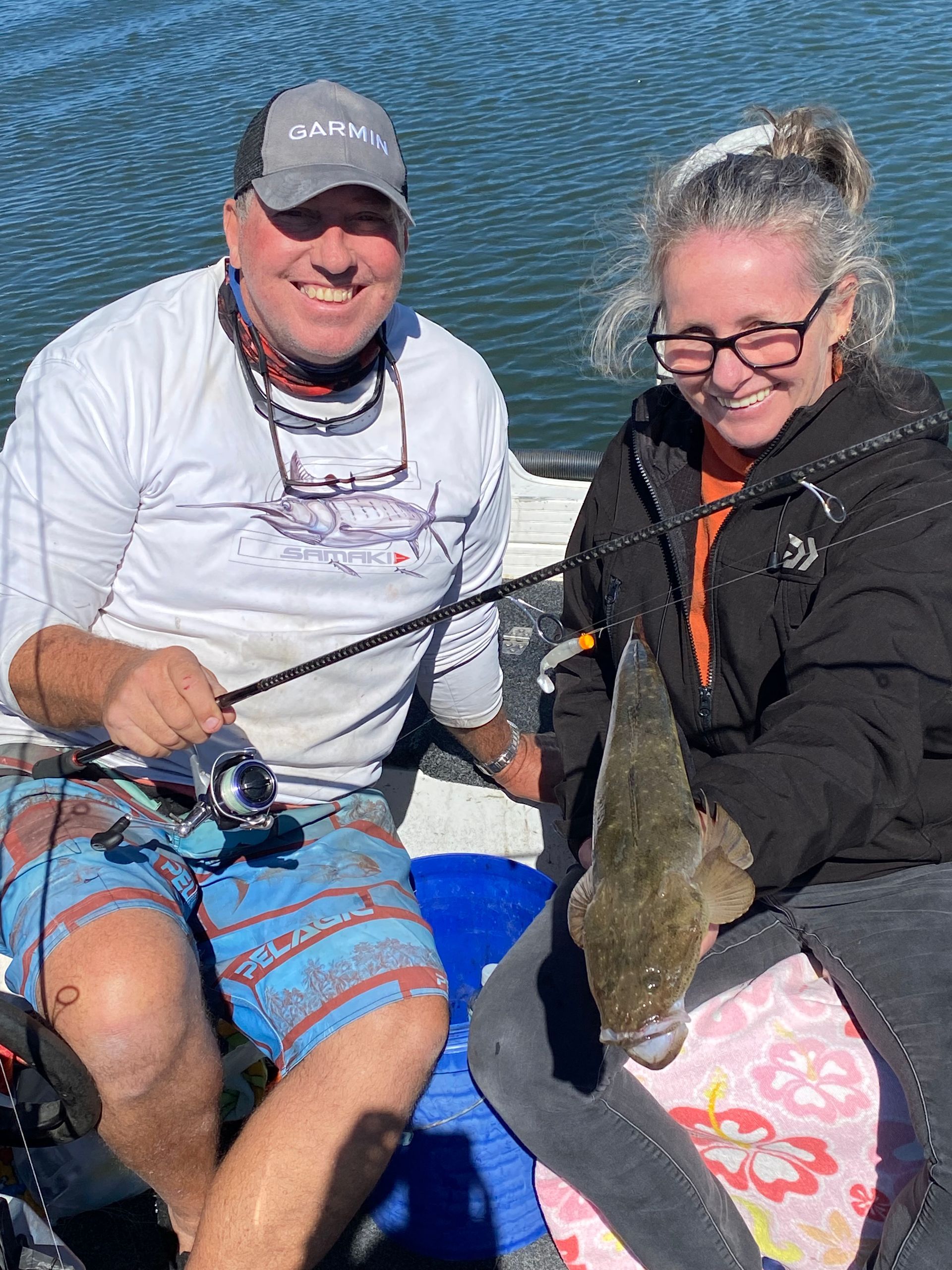 A man and a woman are sitting in a boat holding a fish.