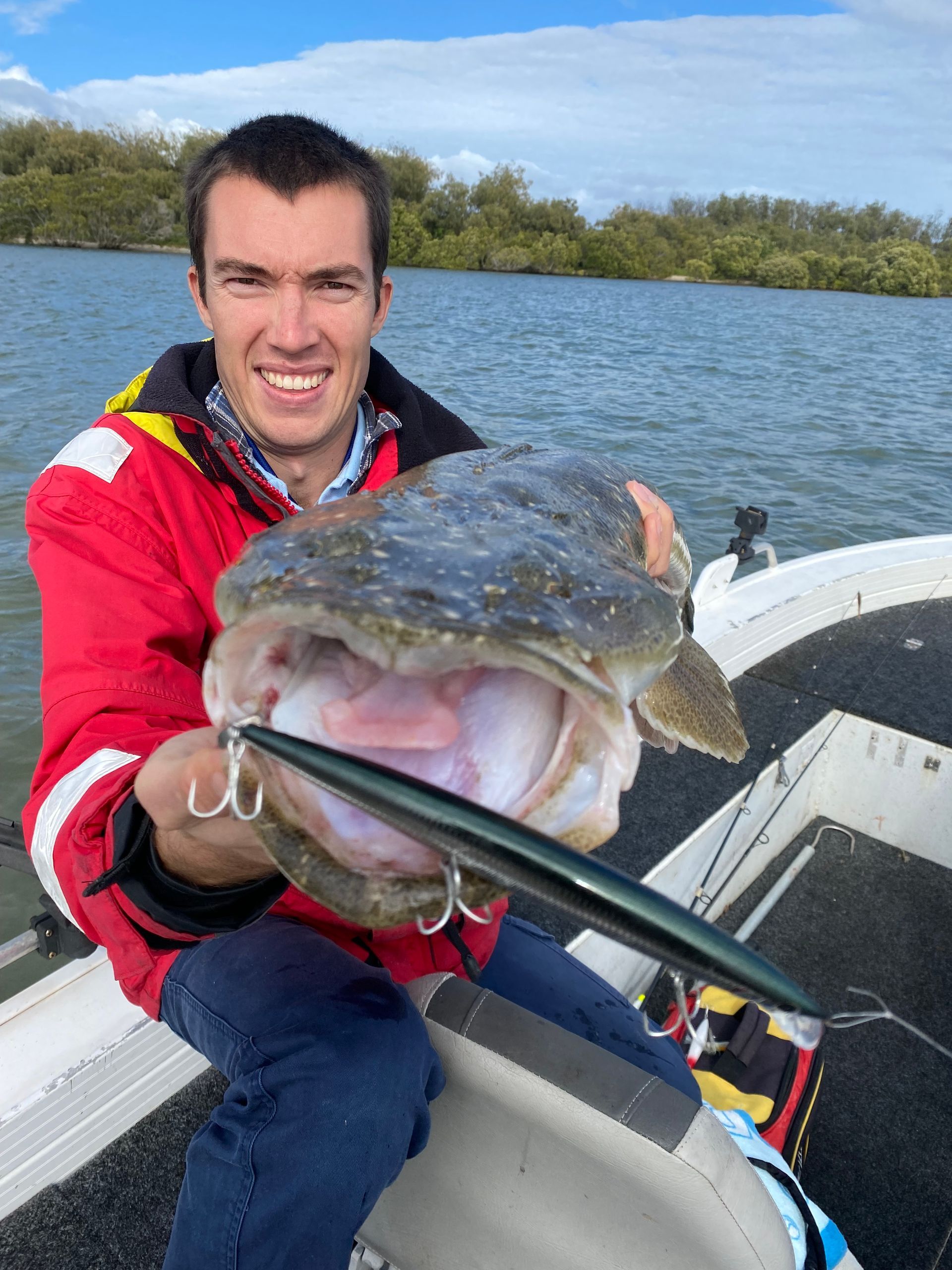 A man is sitting on a boat holding a large fish.