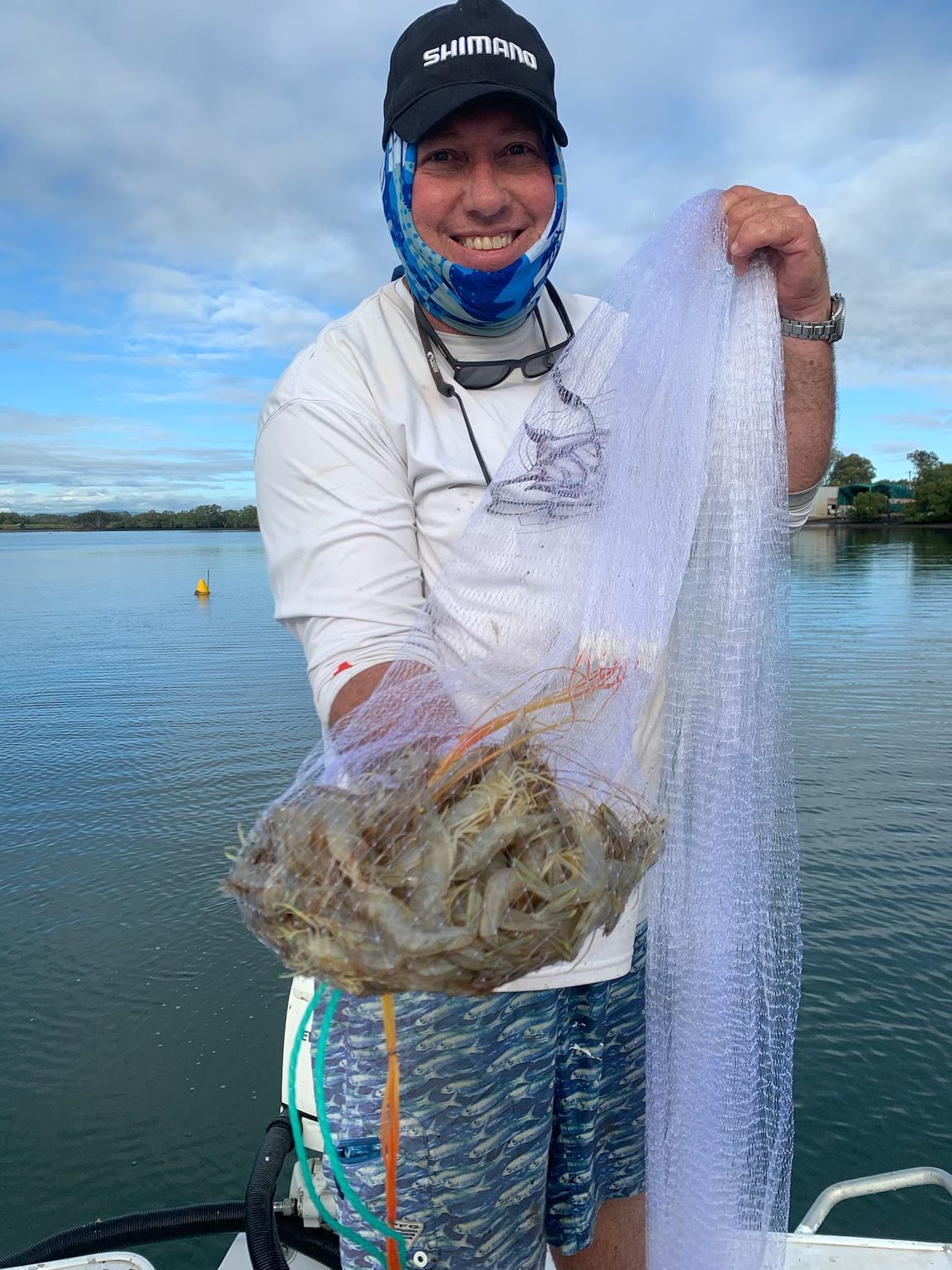 A man is holding a bag of shrimp and a fishing net.