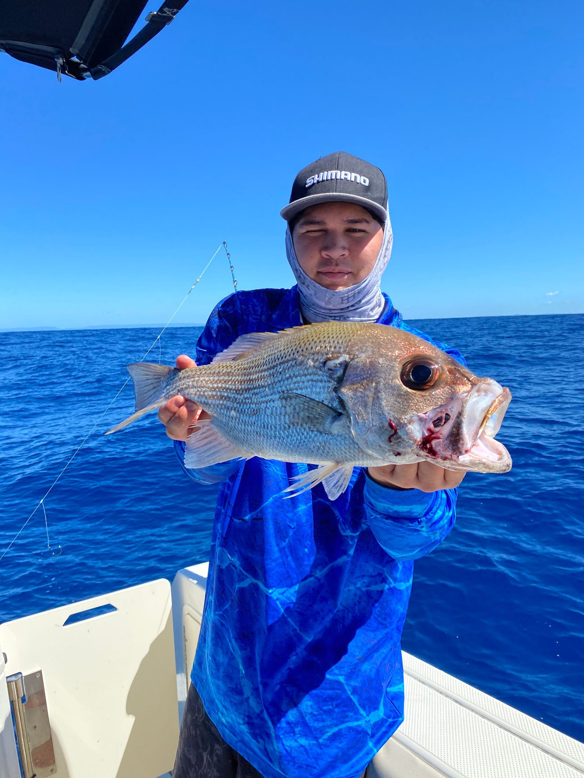 A man is holding a large fish in his hands on a boat.