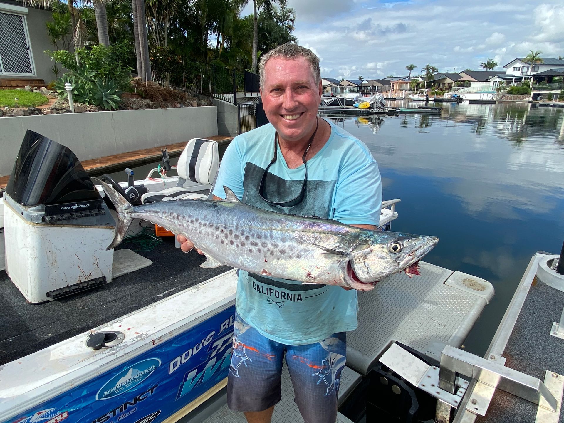 A man is holding a large fish in front of a boat.
