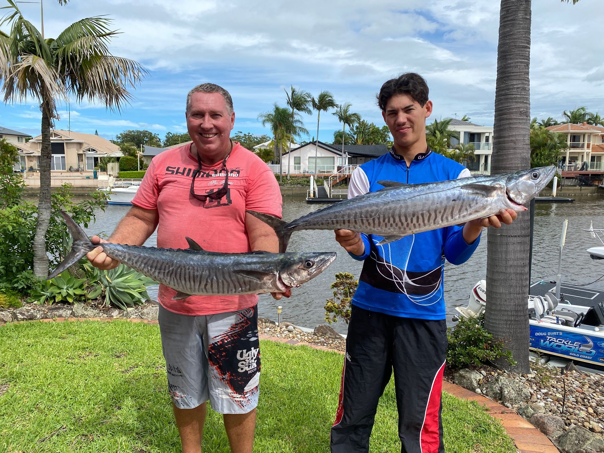 Two men are holding two large fish in their hands.