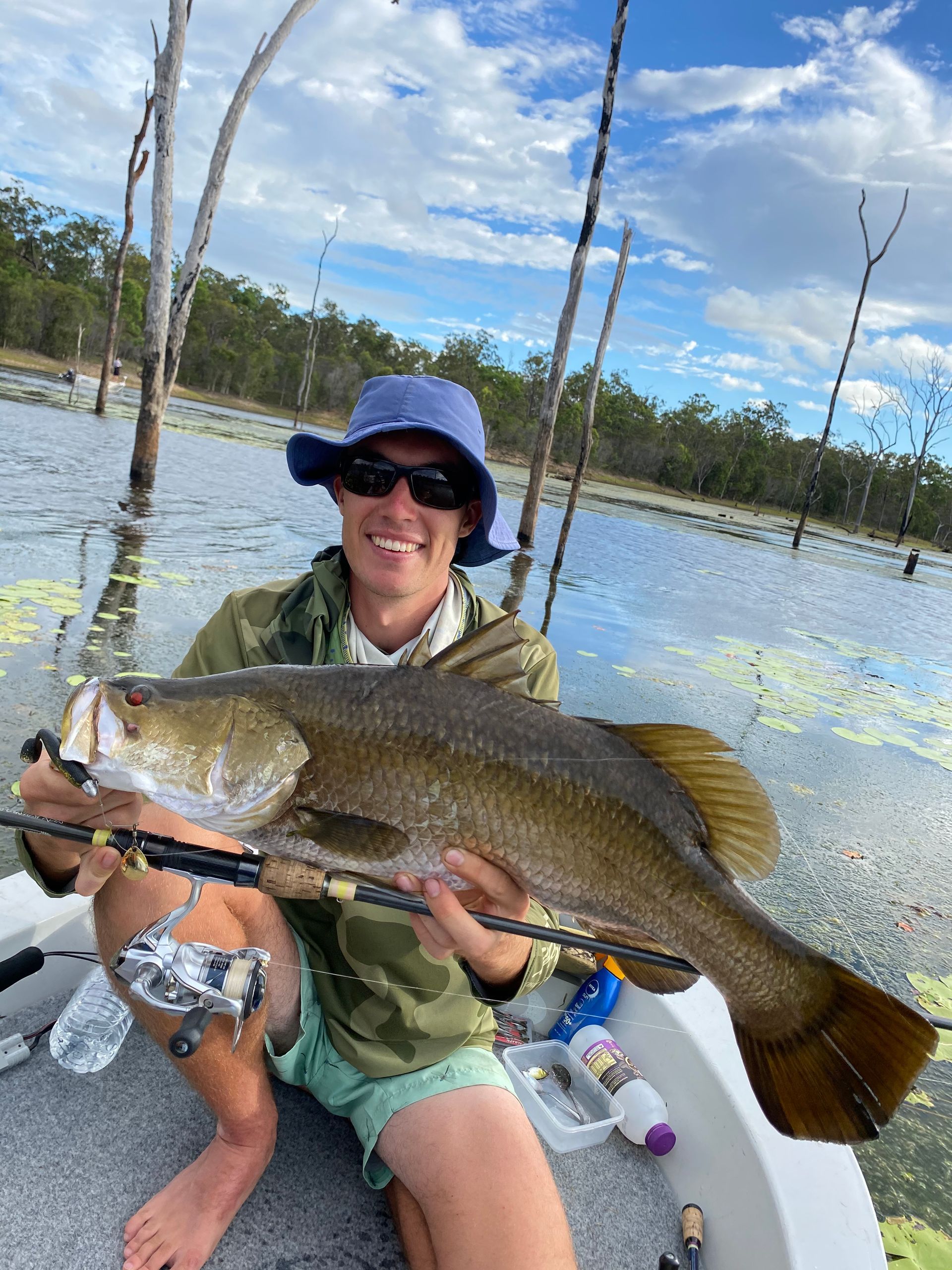 A man is sitting on a boat holding a large fish.