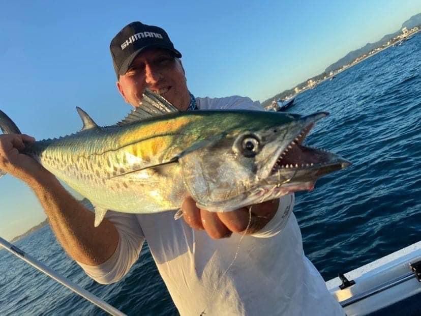 A man is holding a large fish in his hands on a boat