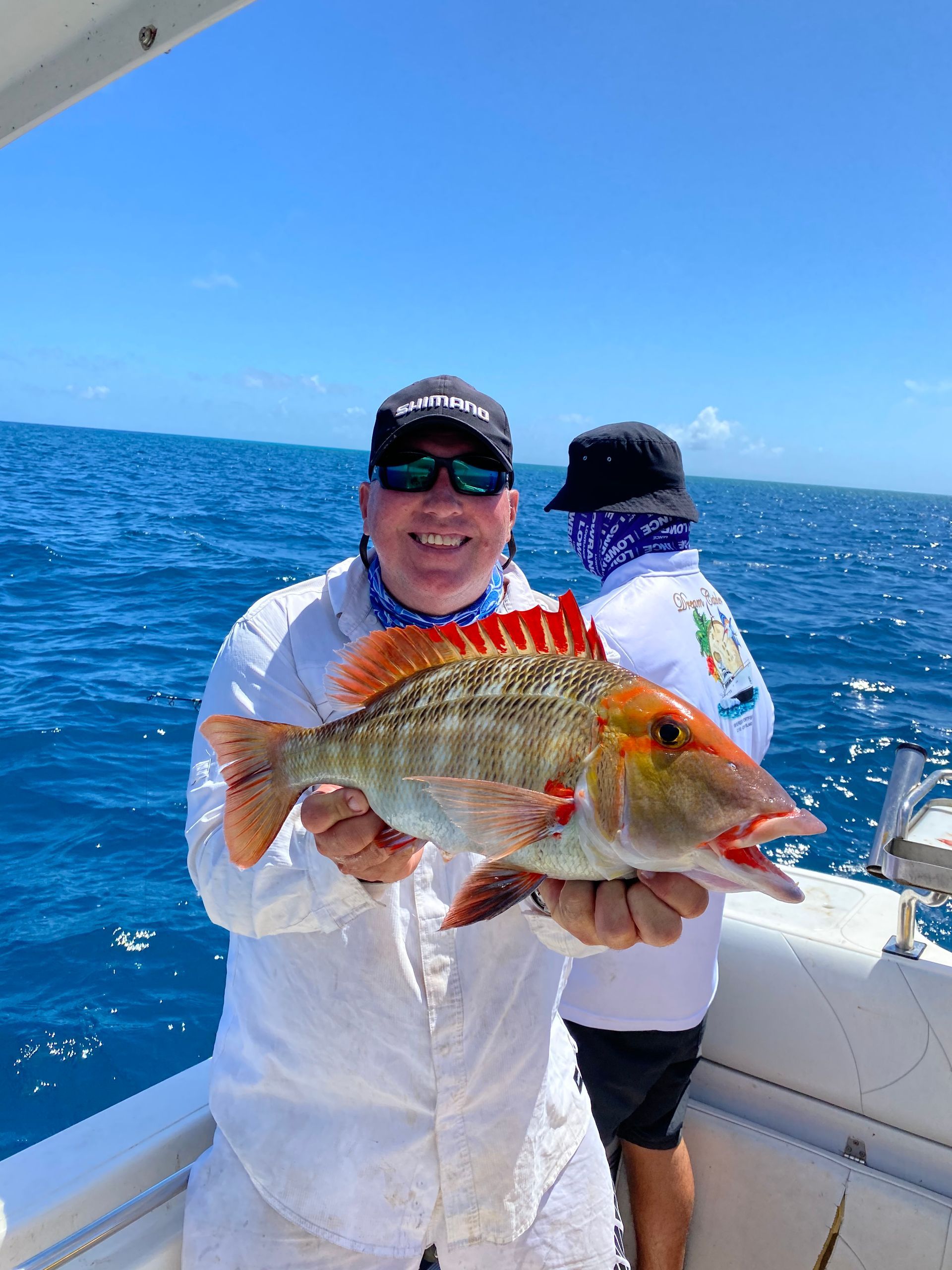 A man is holding a fish on a boat in the ocean.