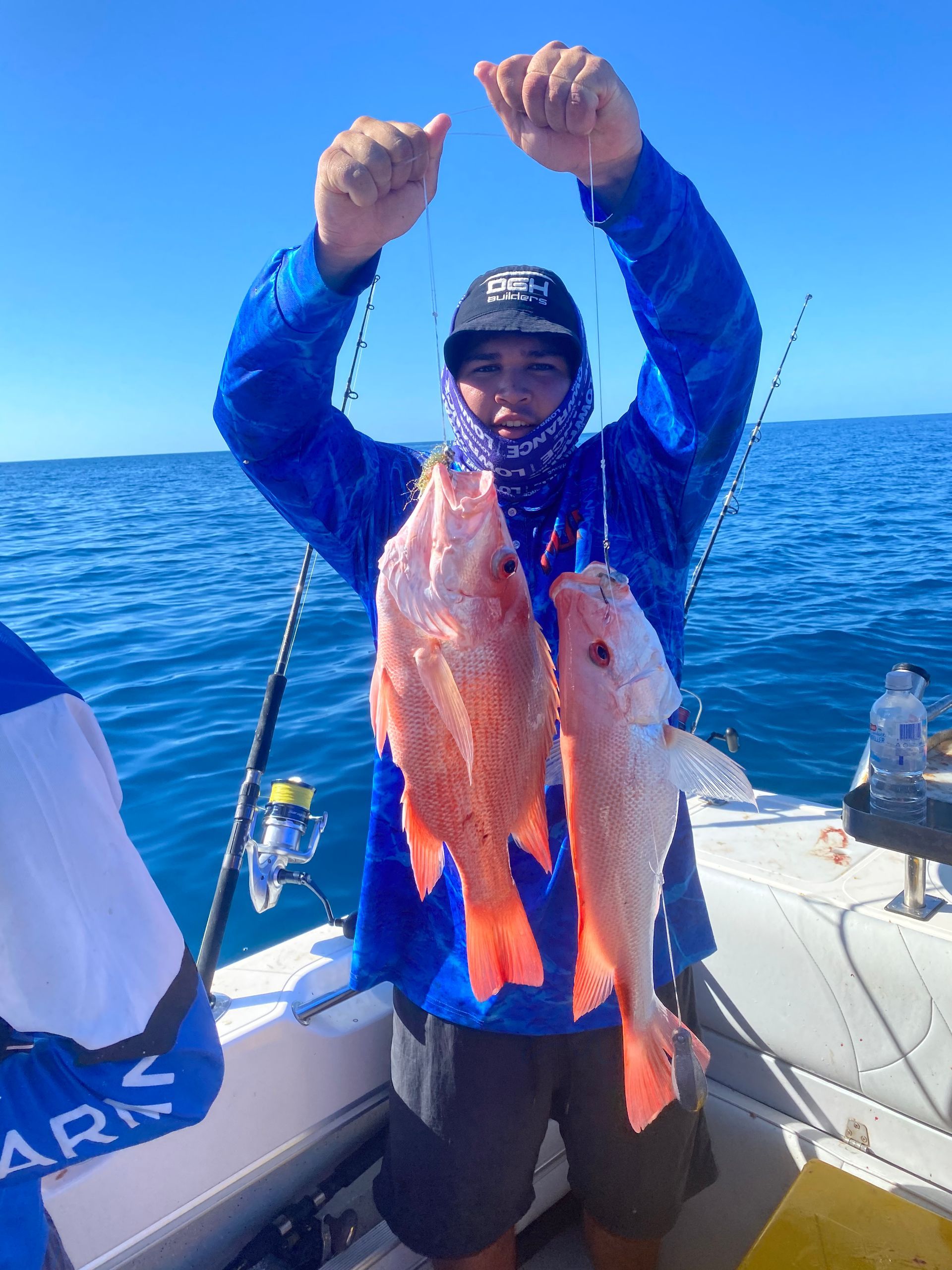 A man on a boat is holding two fish in his hands