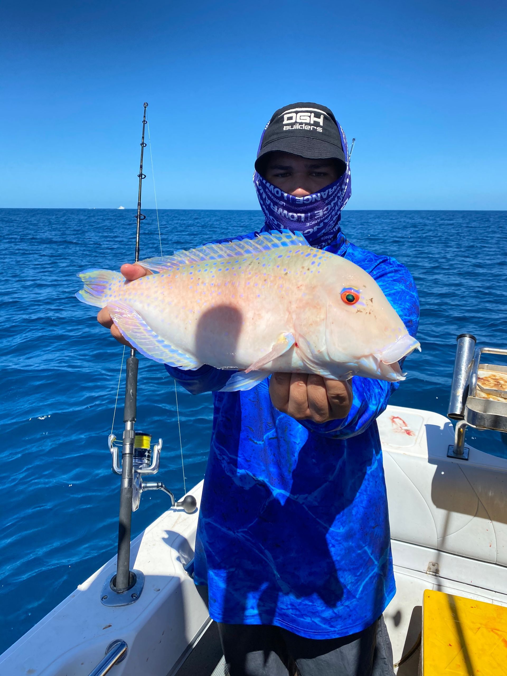 A man is holding a fish on a boat in the ocean.