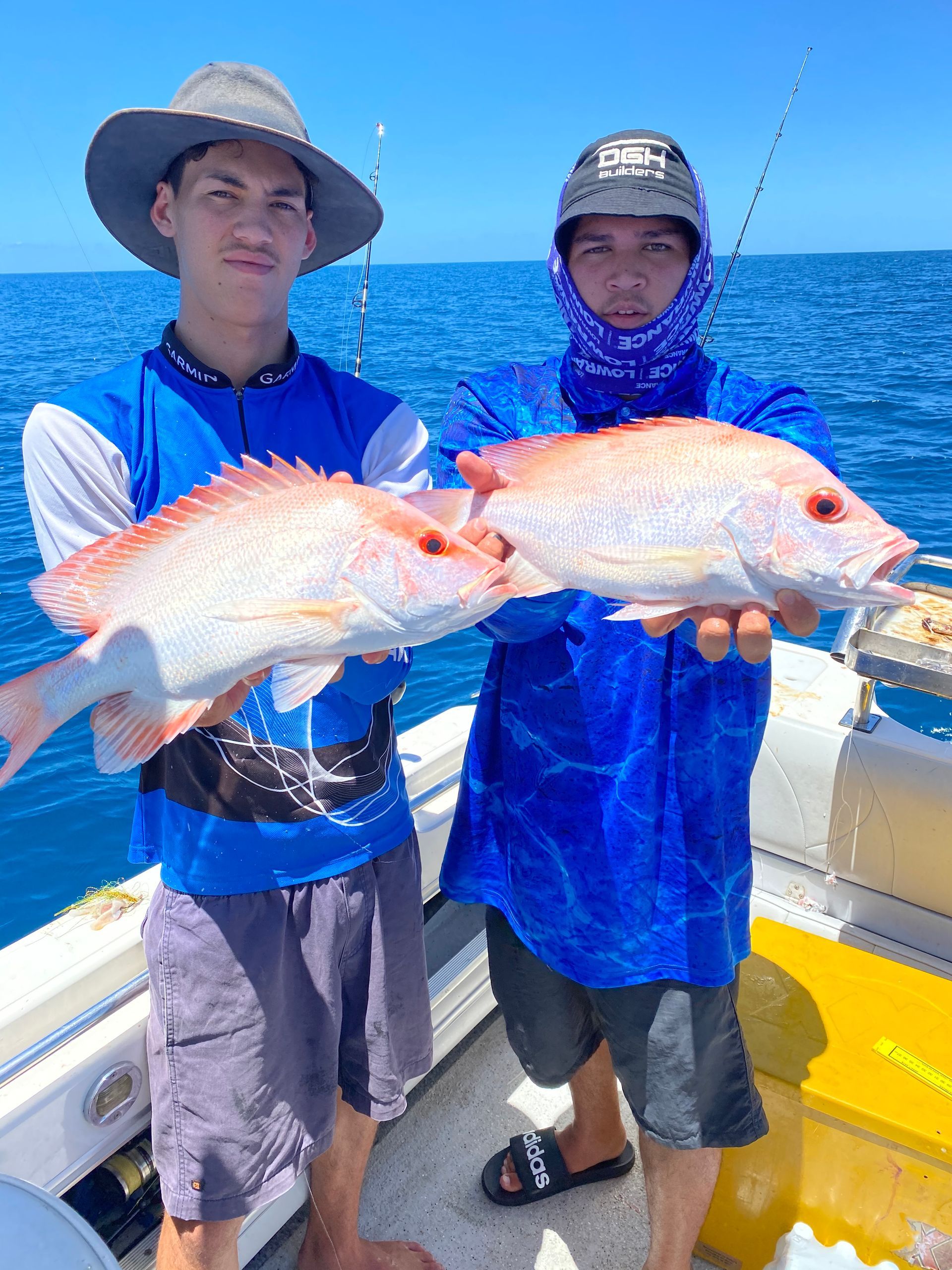 Two men are holding two fish on a boat in the ocean.
