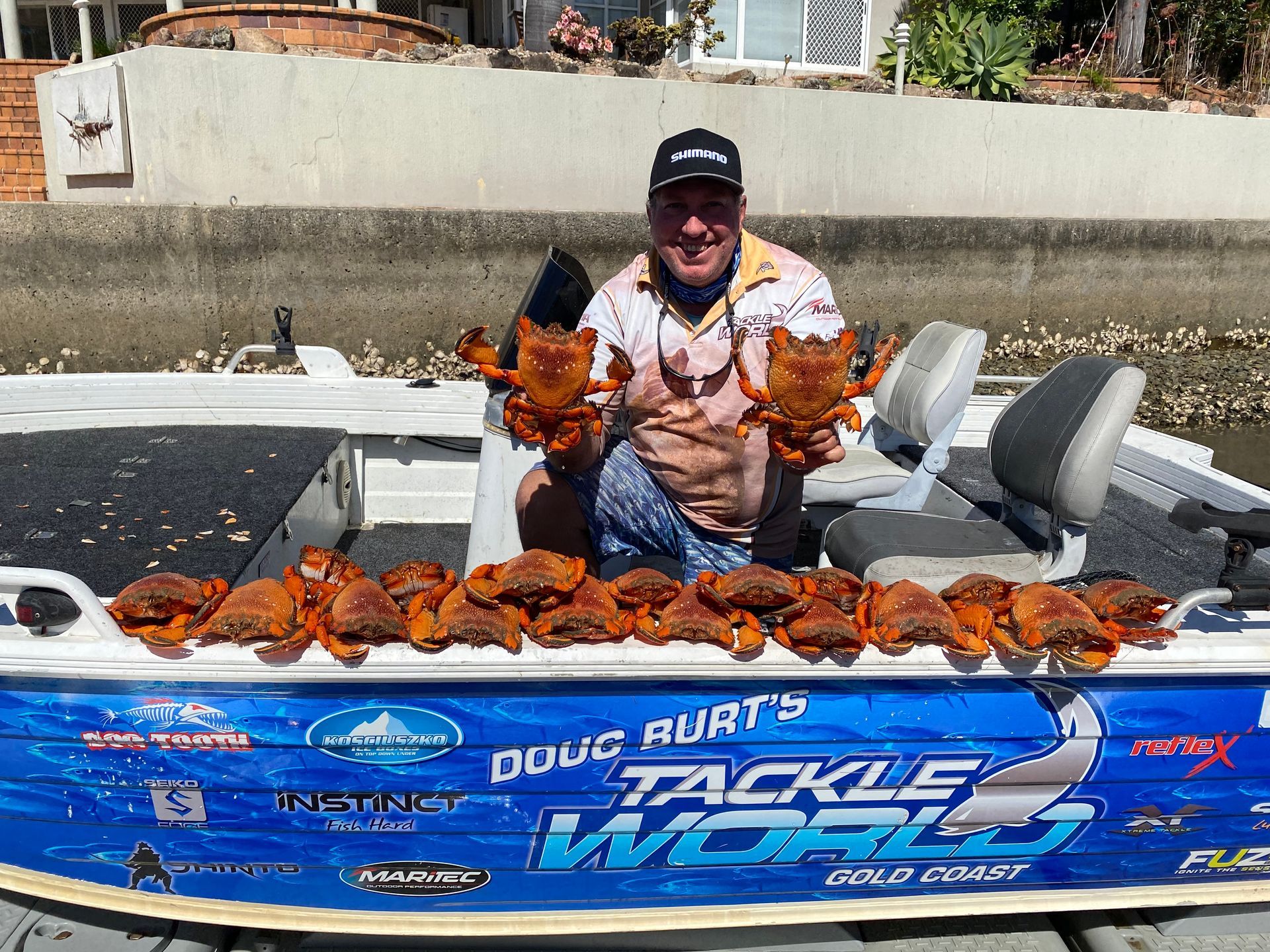 A man is sitting on a boat holding a bunch of crabs.