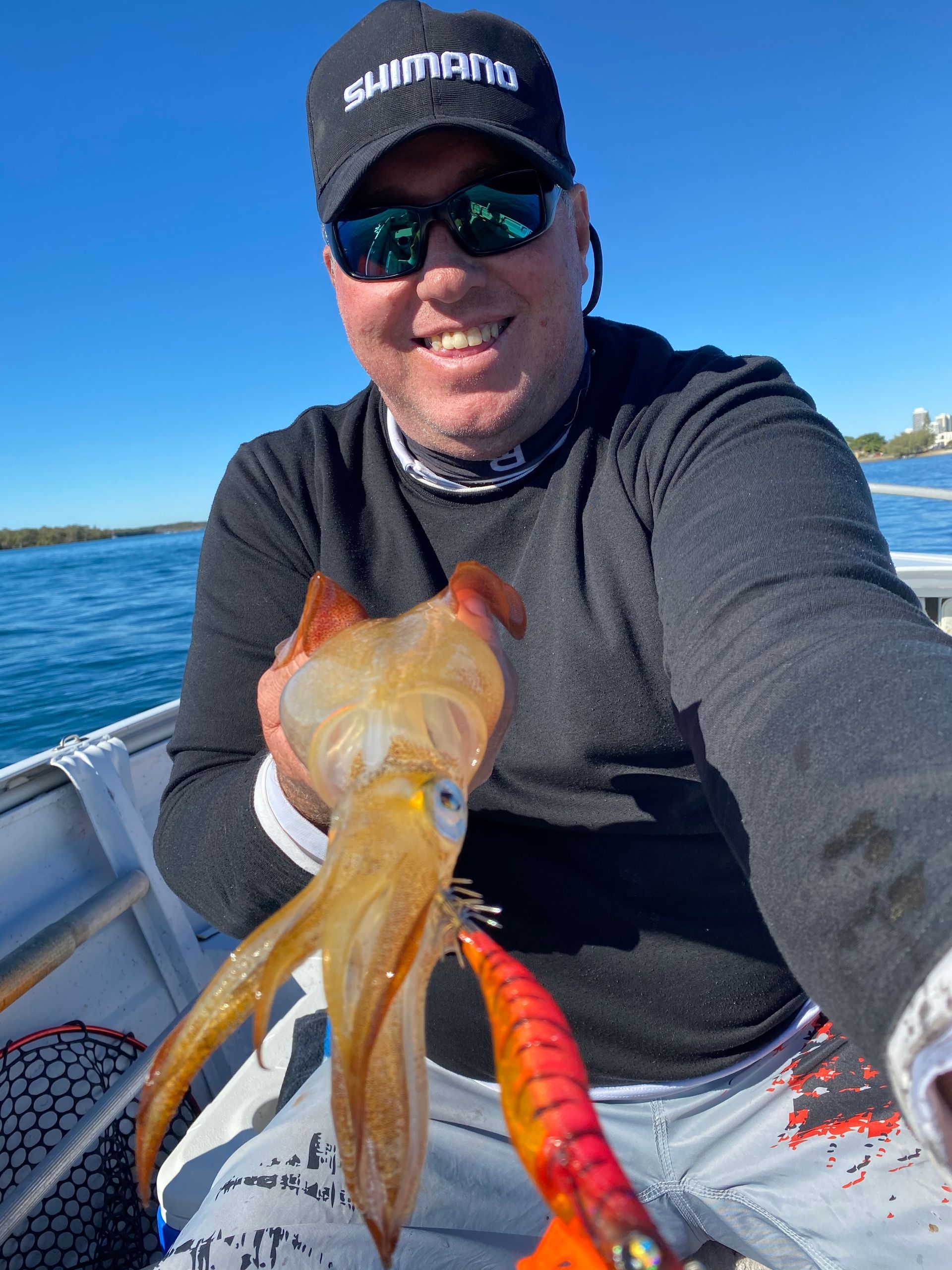 A man is sitting on a boat holding a squid.