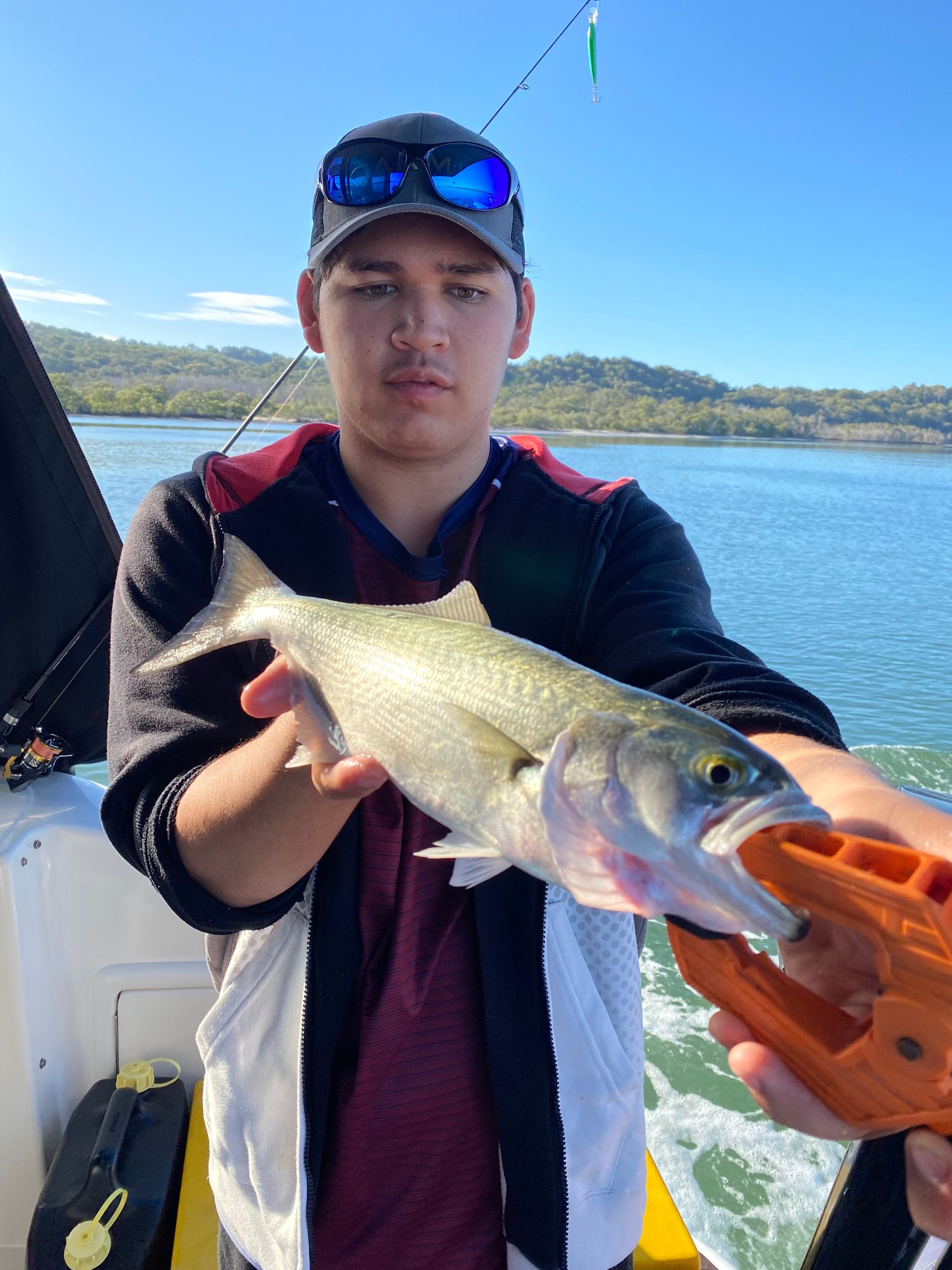 A young man is holding a fish in his hands on a boat