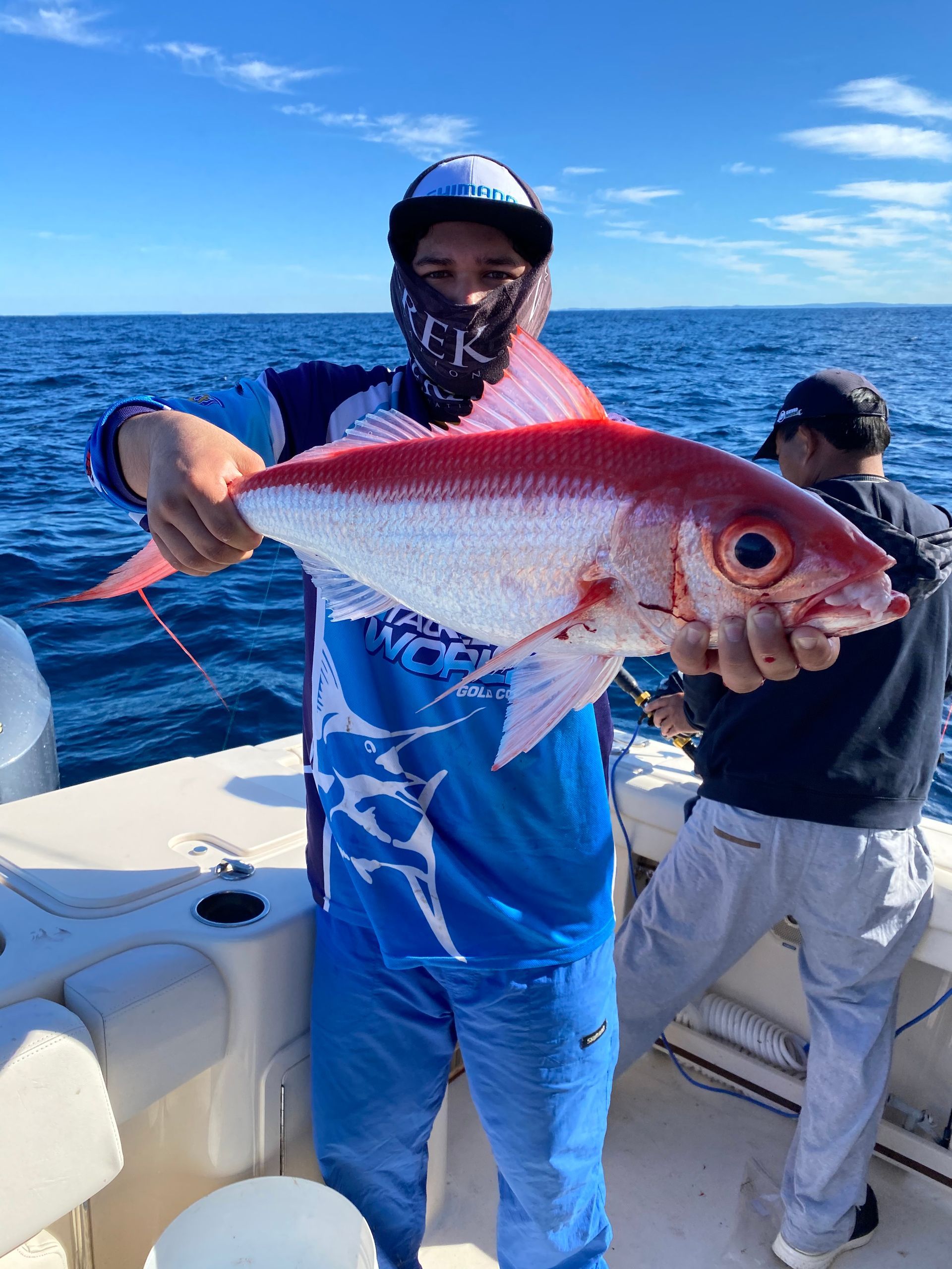 A man is holding a red fish on a boat.