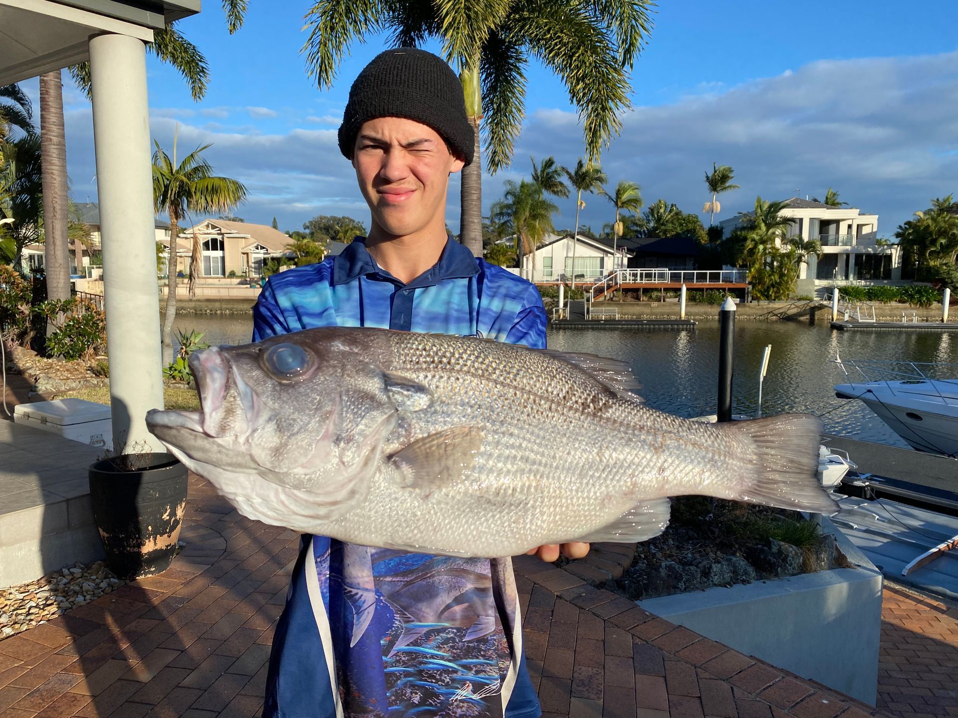 A young man is holding a large fish in his hands.