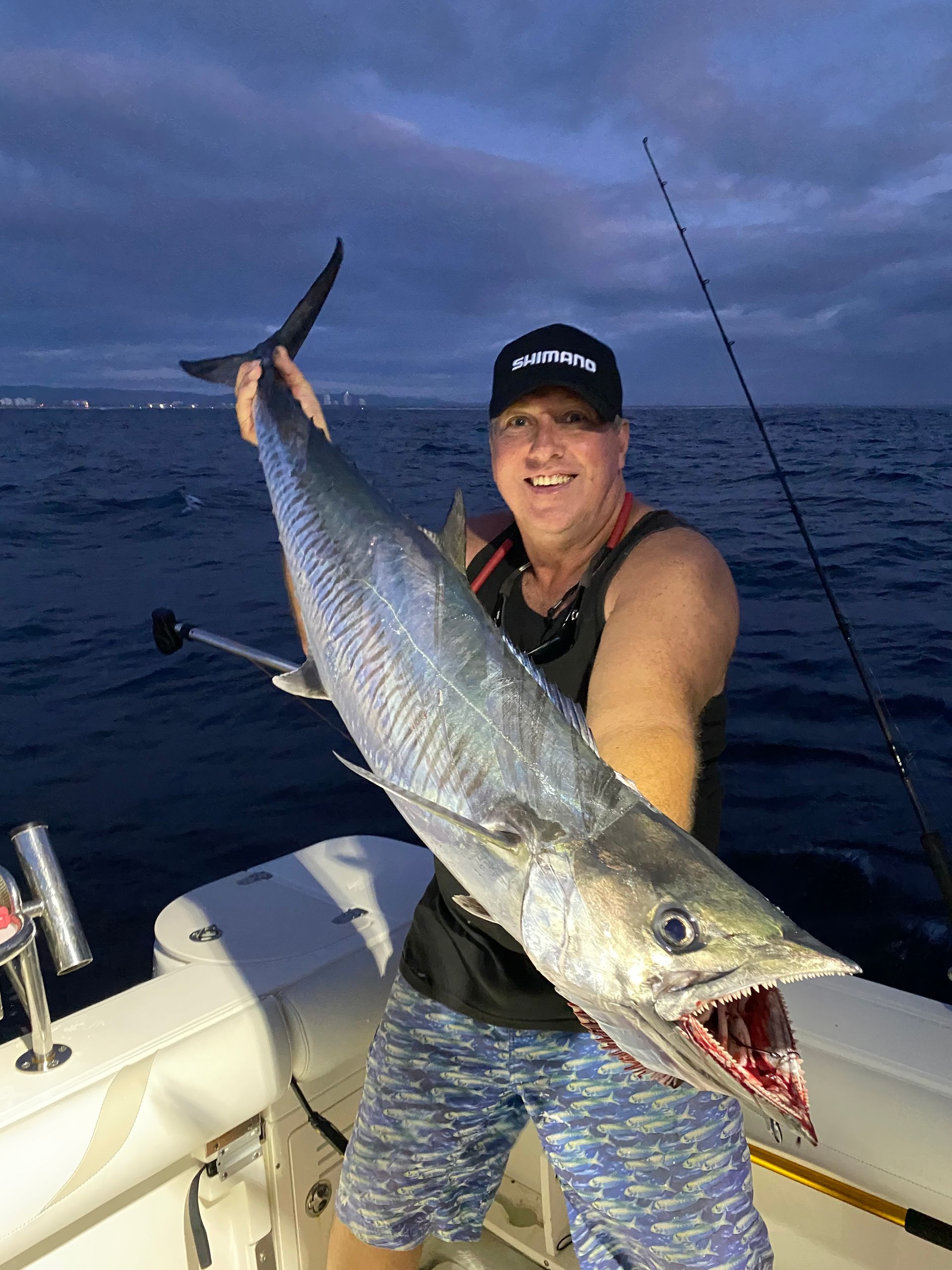 A man is holding a large fish on a boat in the ocean.