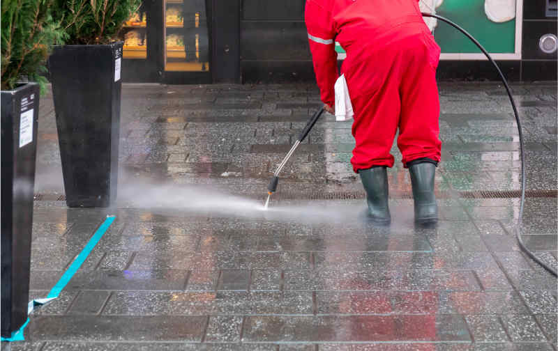 A professional power washing a commercial outdoor space