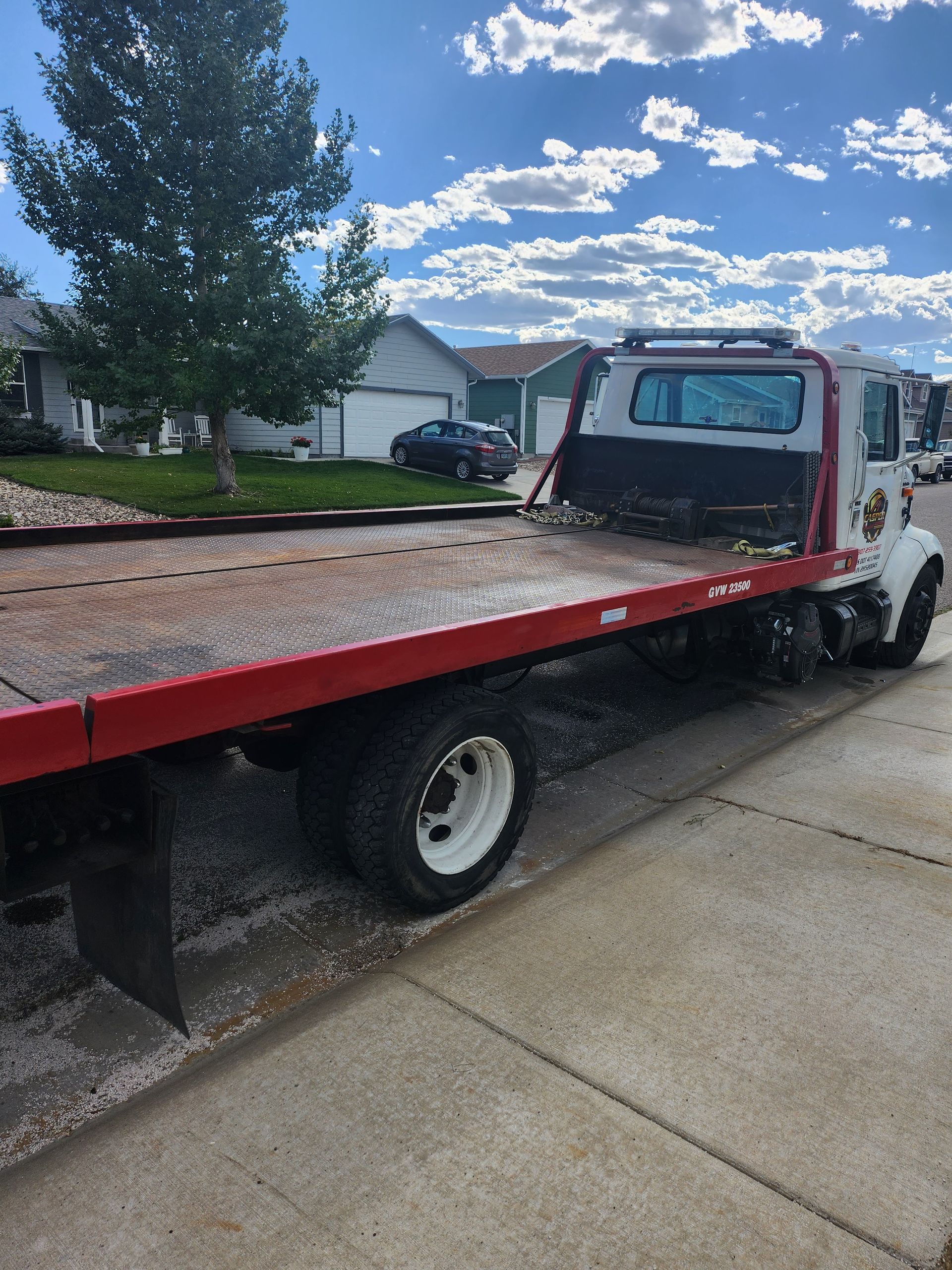 A red and white tow truck is parked on the side of the road.