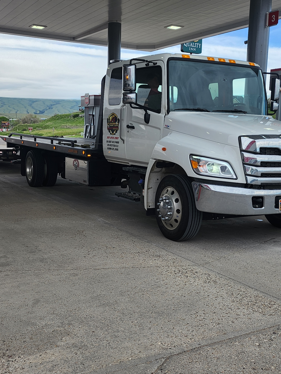 A white tow truck is parked on the side of the road.