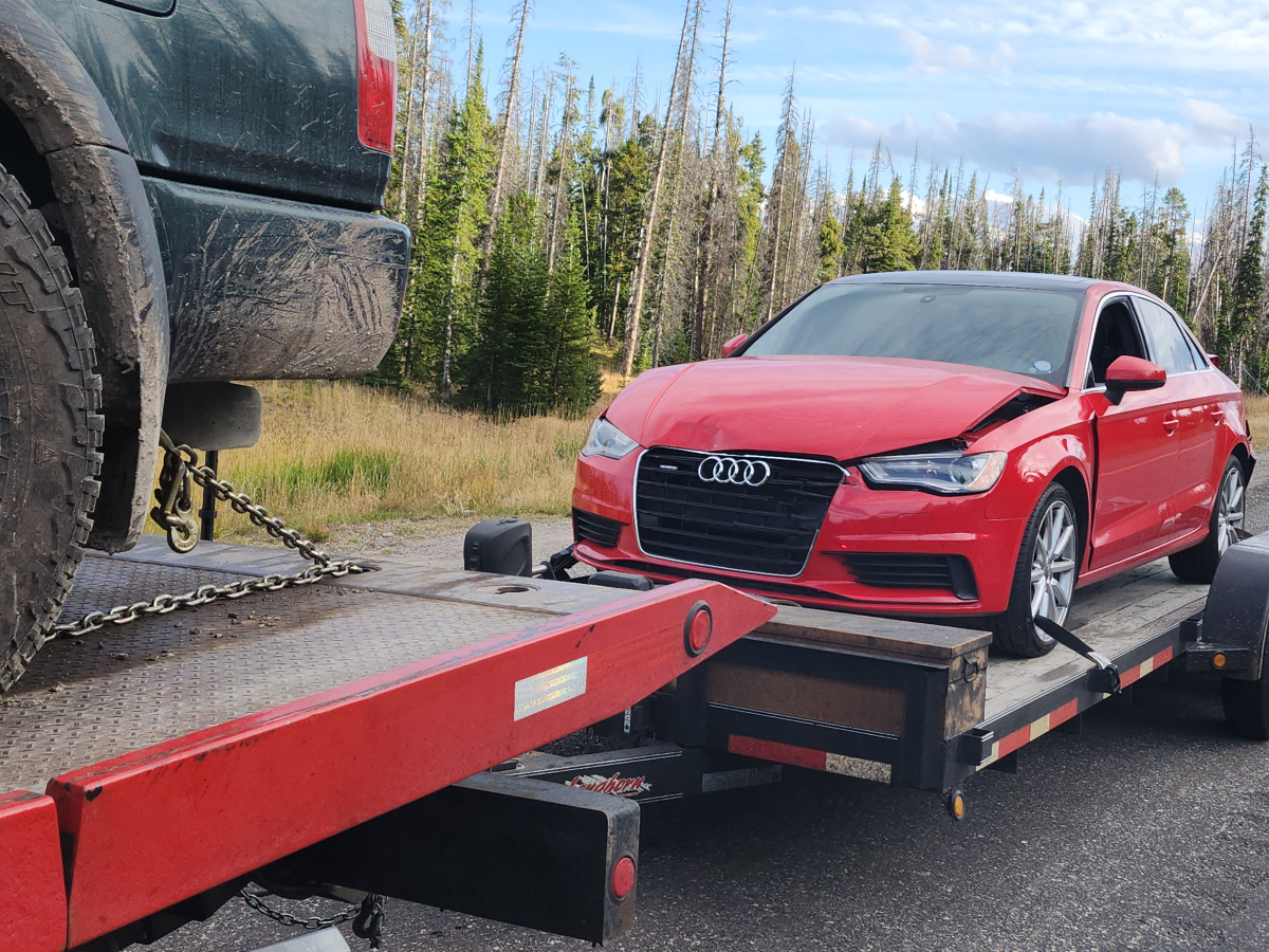 A red car is being towed by a tow truck.