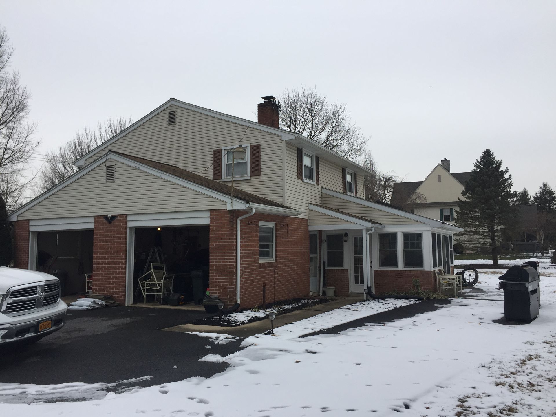 Snowy suburban house with open garage and parked truck on the left
