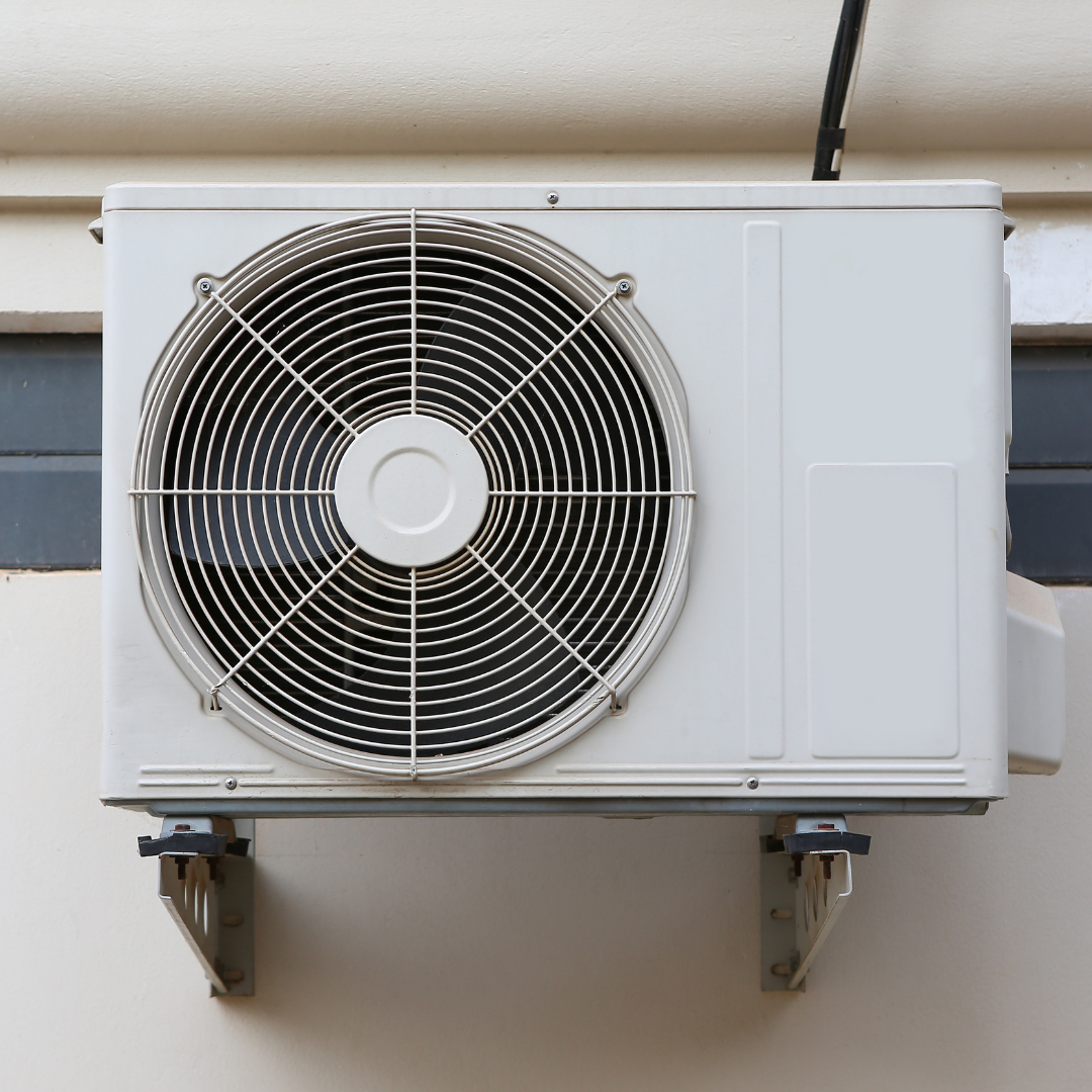 A white air conditioner is mounted on the side of a building.