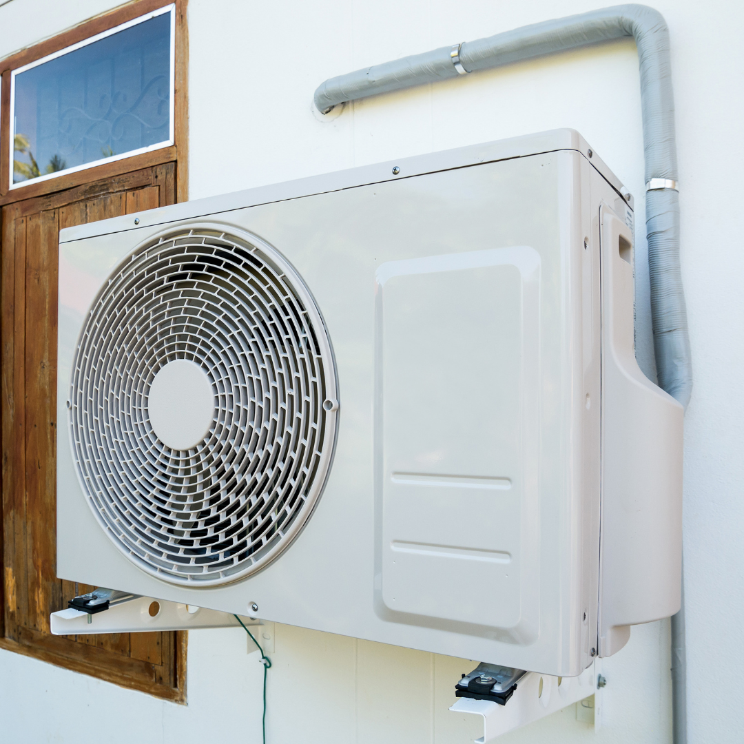 A white air conditioner is mounted on the side of a building