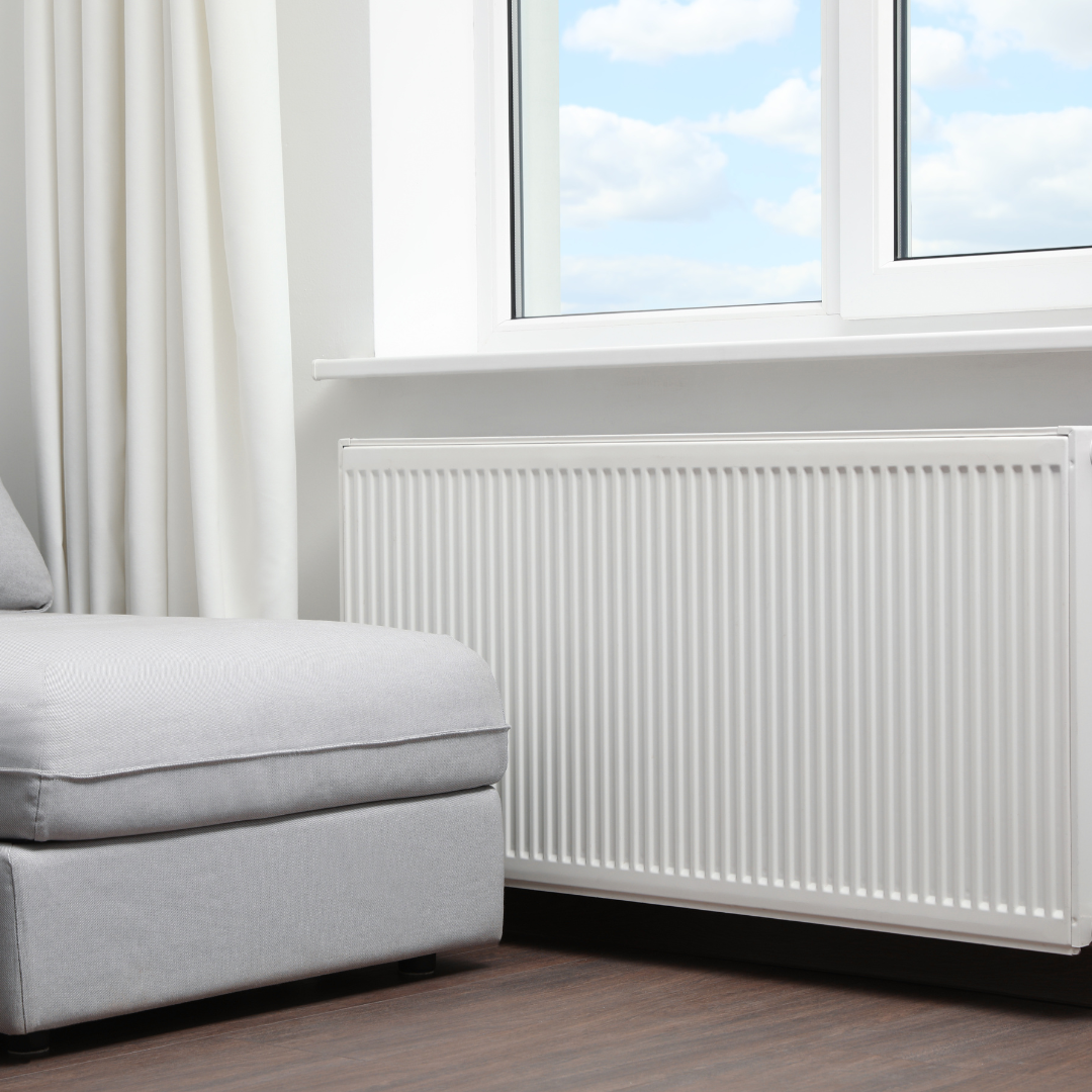A living room with a couch , ottoman , and radiator.