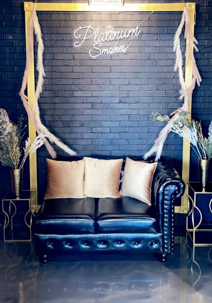 A black couch is sitting in front of a brick wall.