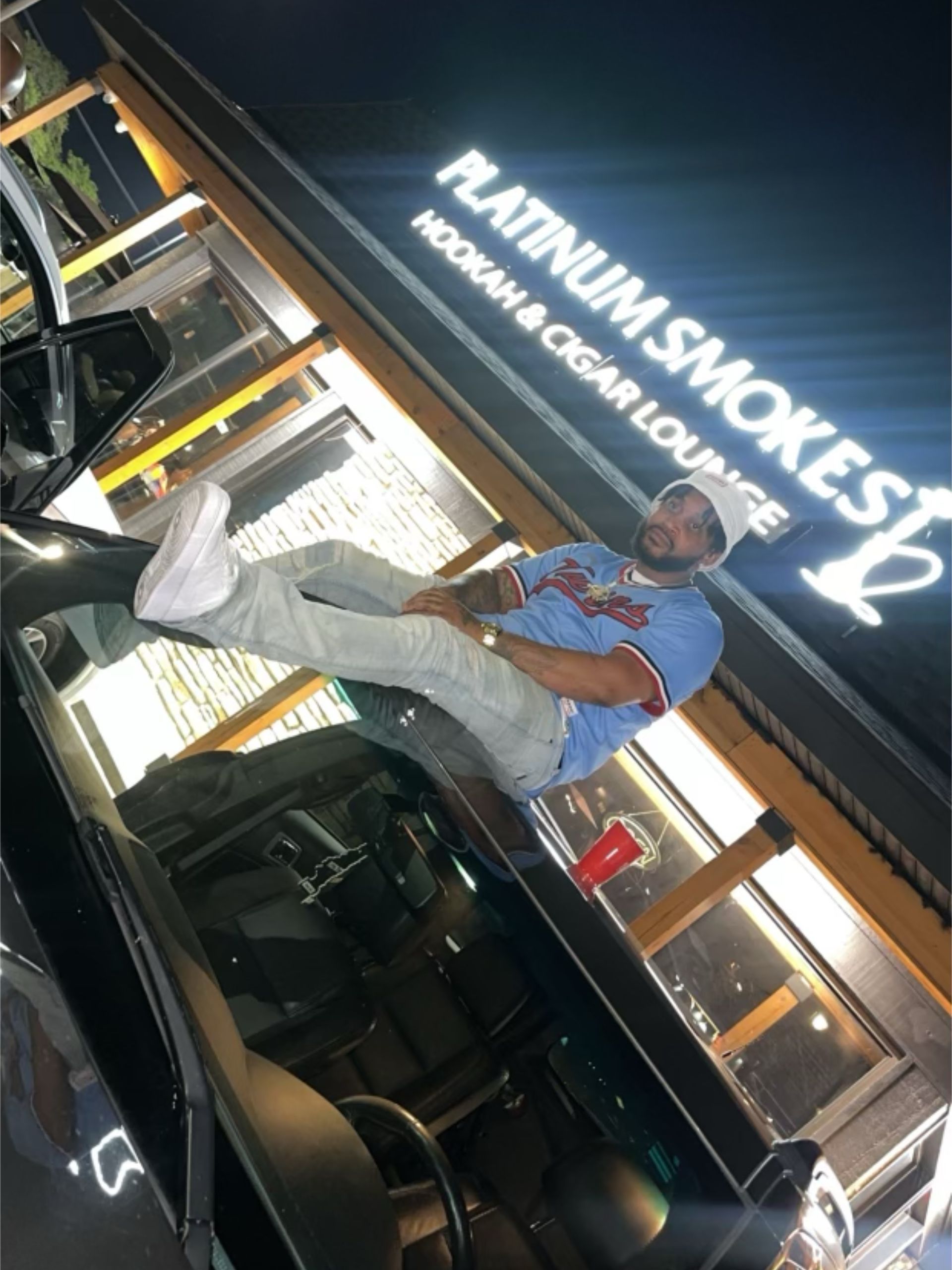 Man lounging on a car roof outside 