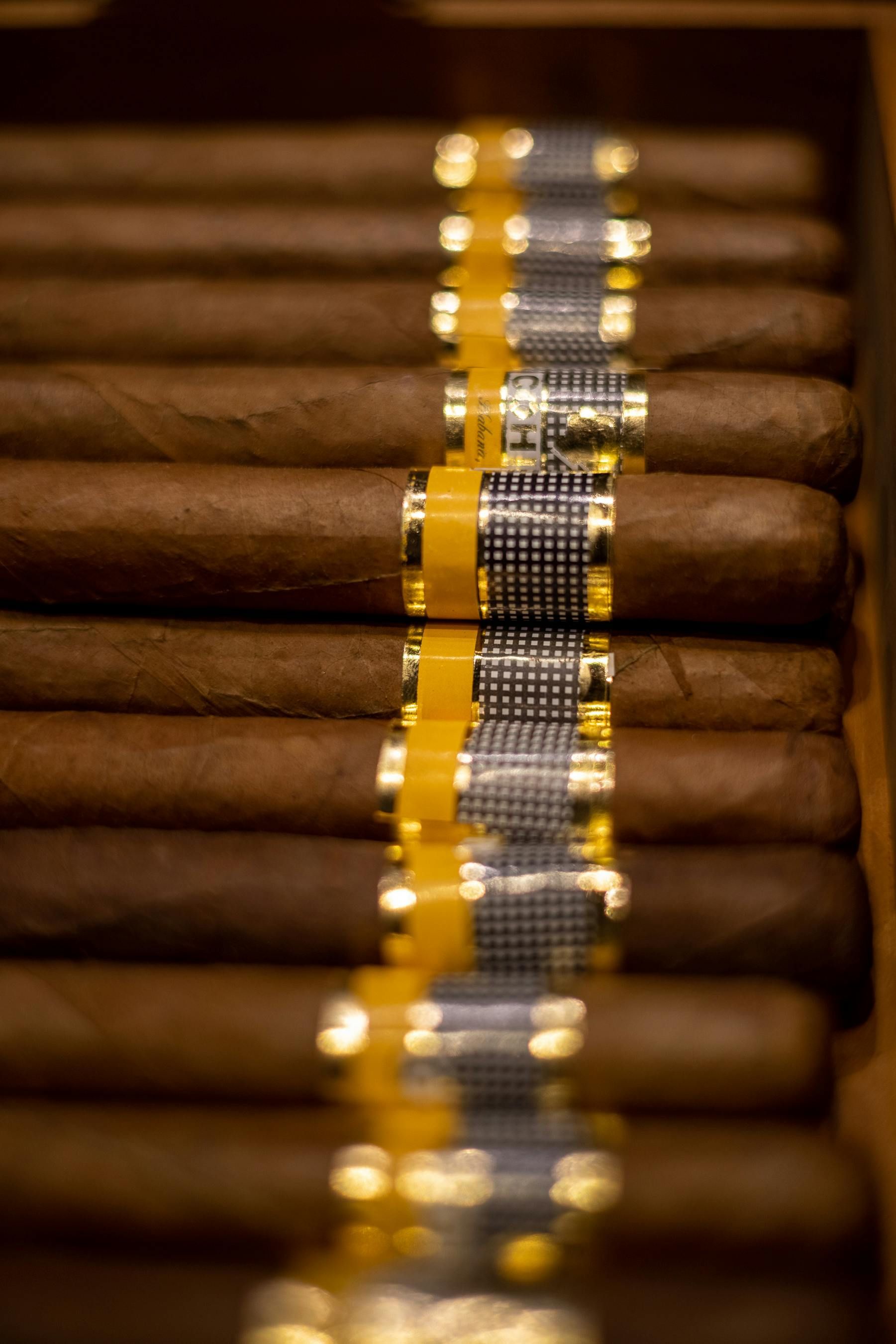 A row of cigars are lined up in a wooden box.