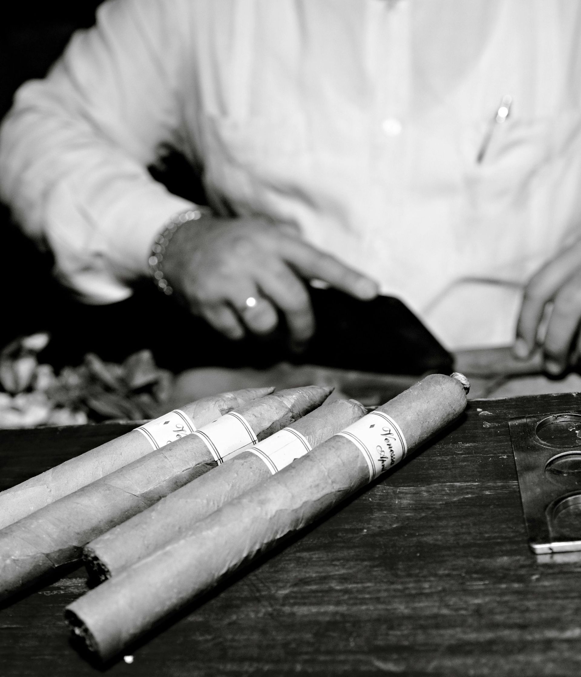 A black and white photo of a man making cigars