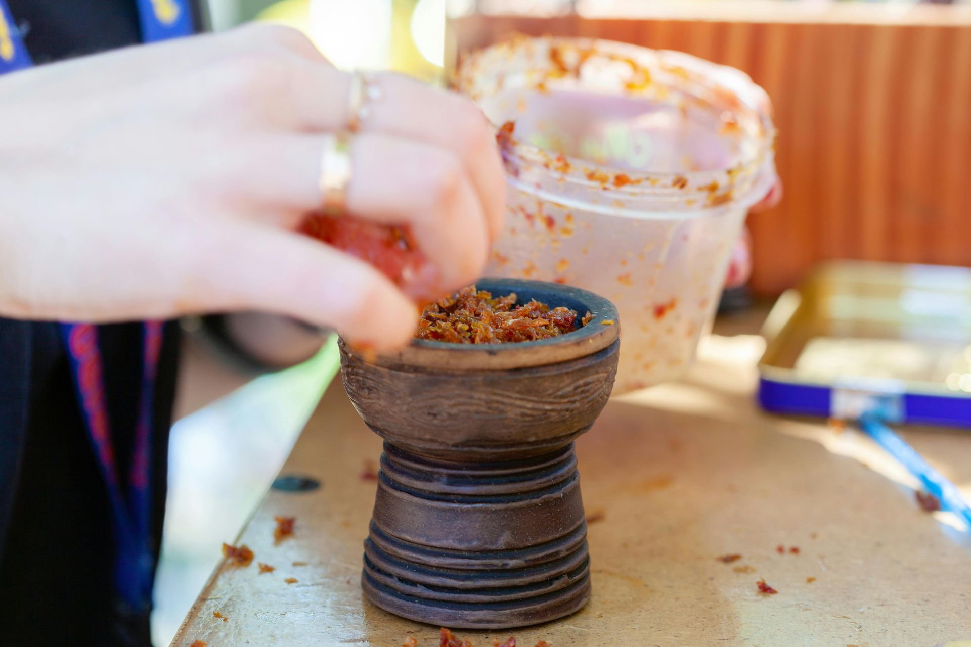 A person is making a hookah with tobacco in a bowl.