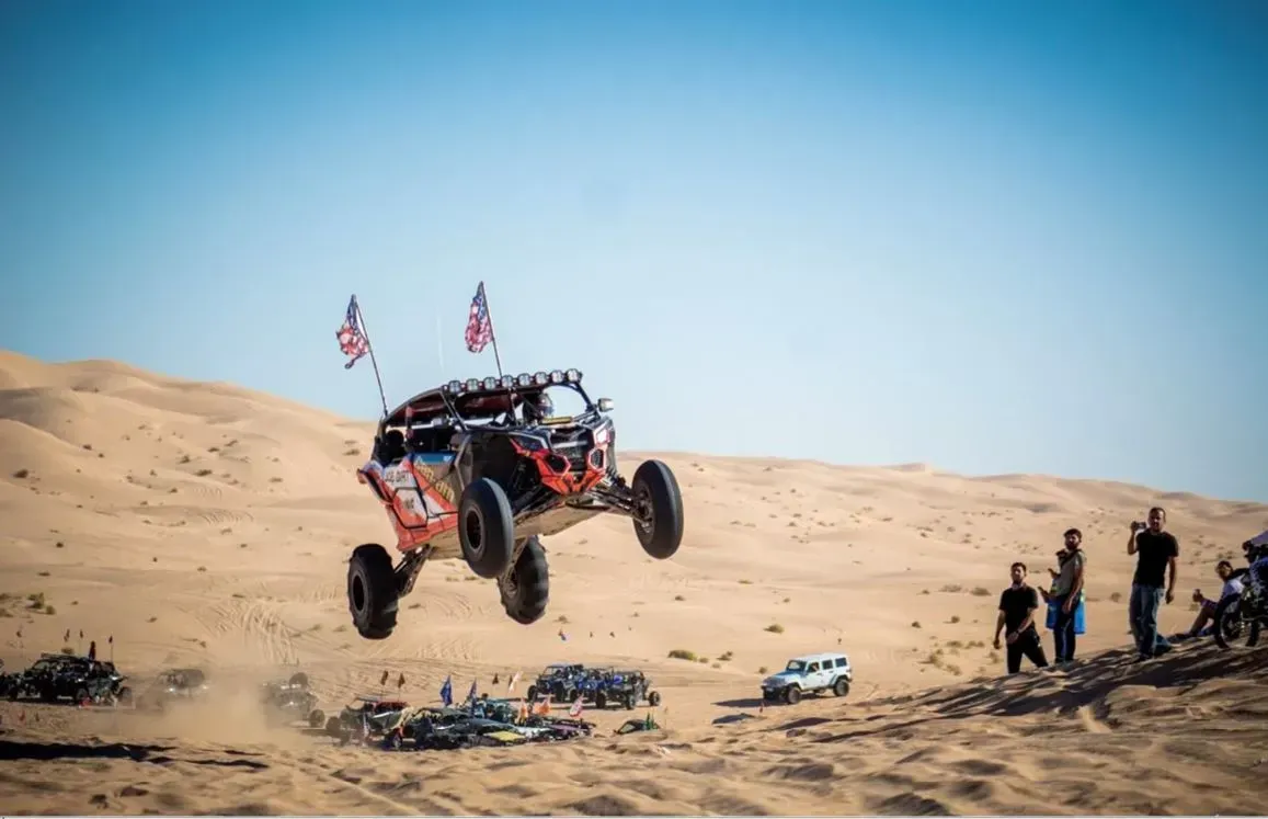A dune buggy is jumping in the air in the desert.