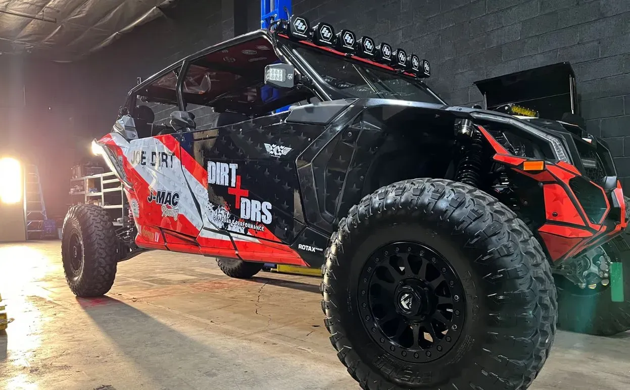 A red and black atv is parked in a garage.