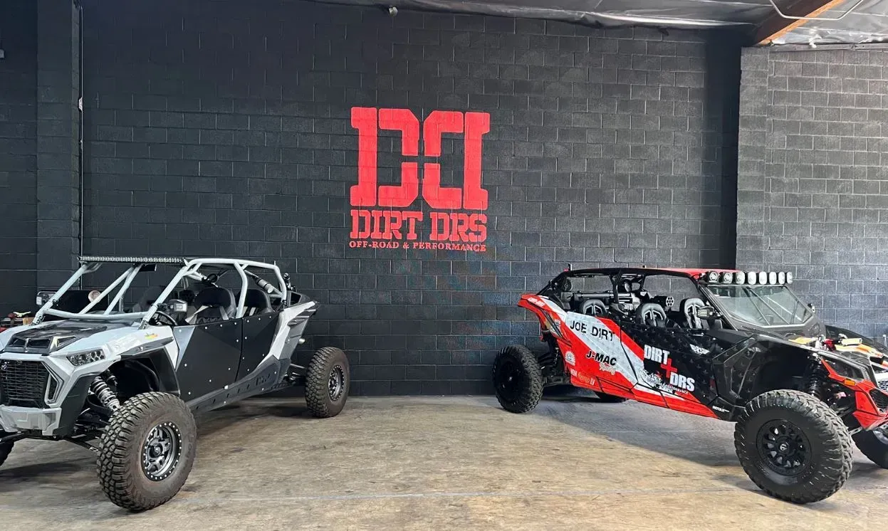 Two atvs are parked in a garage in front of a brick wall.