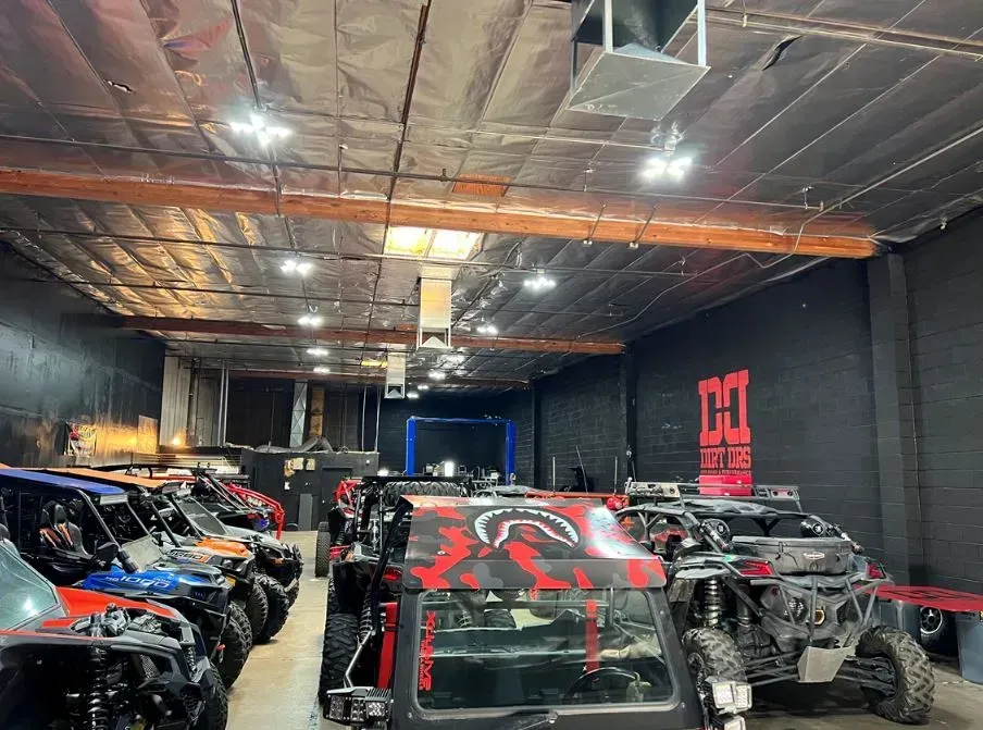A row of atvs are parked in a warehouse.
