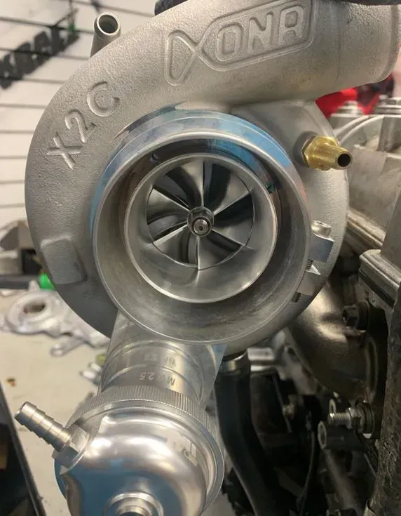 A turbocharger is sitting on top of a car engine.