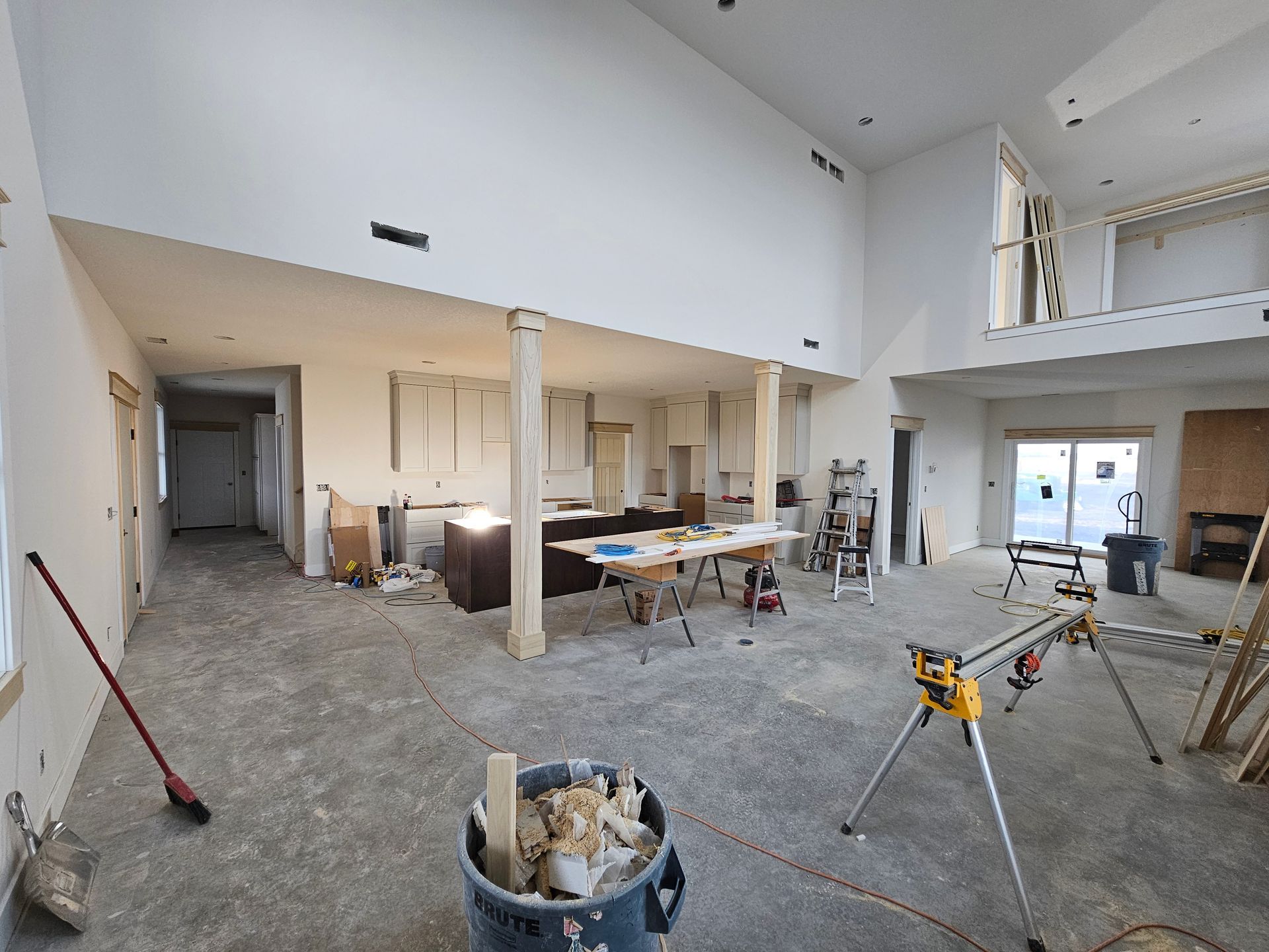 Open-concept kitchen and living area under construction with concrete floors and new cabinetry