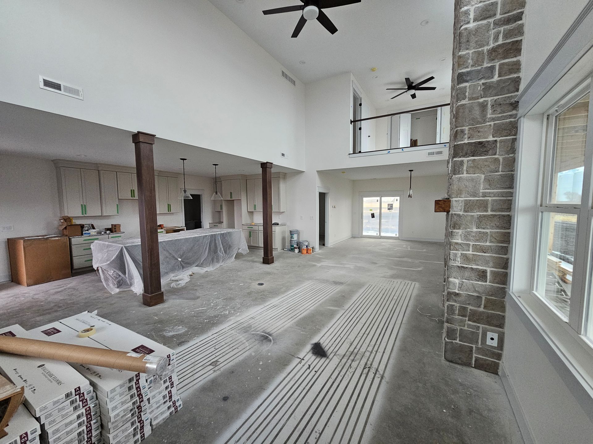 Modern home interior with concrete floors prepped for vinyl plank and stained support columns