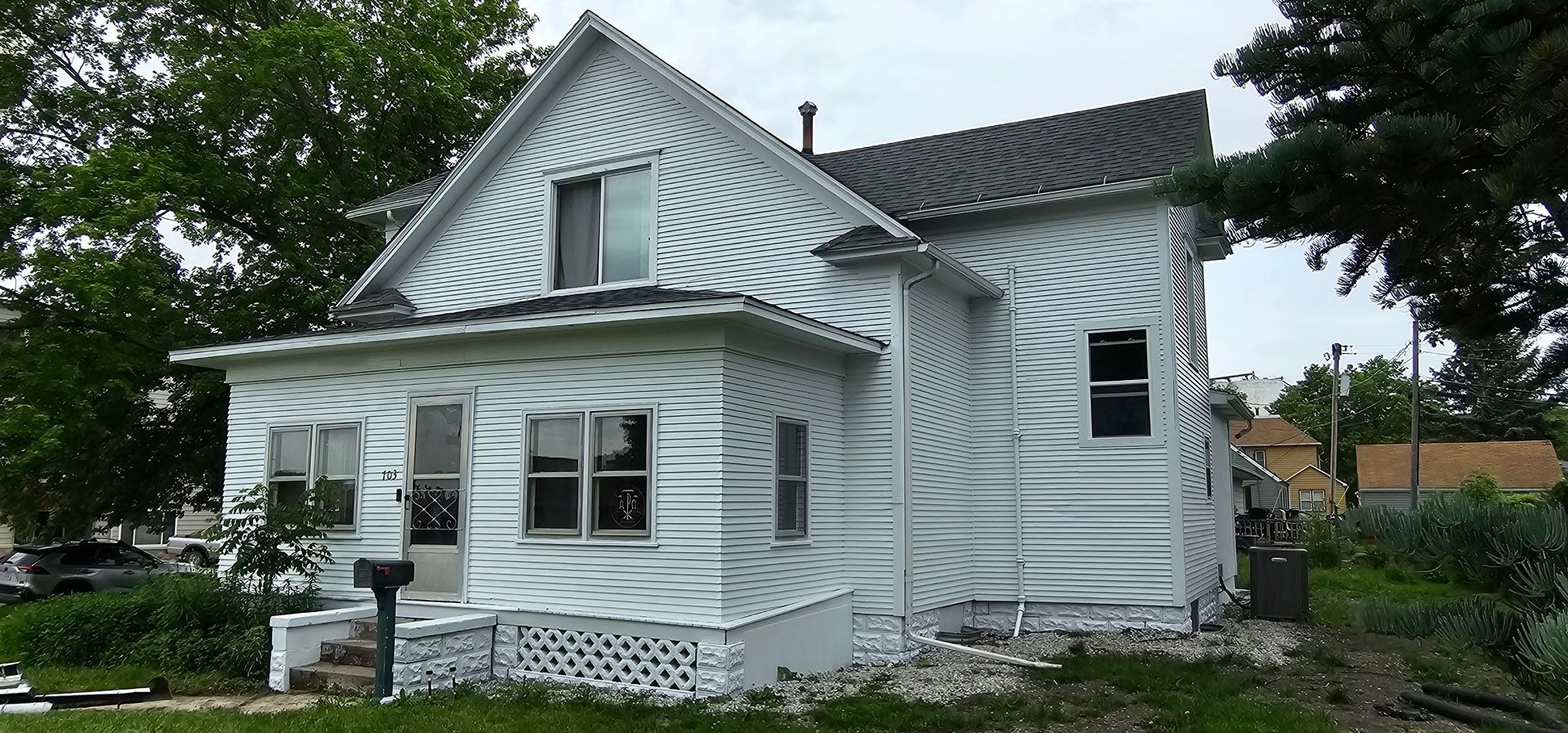 Freshly painted white two-story home with restored siding and clean landscaping after renovation